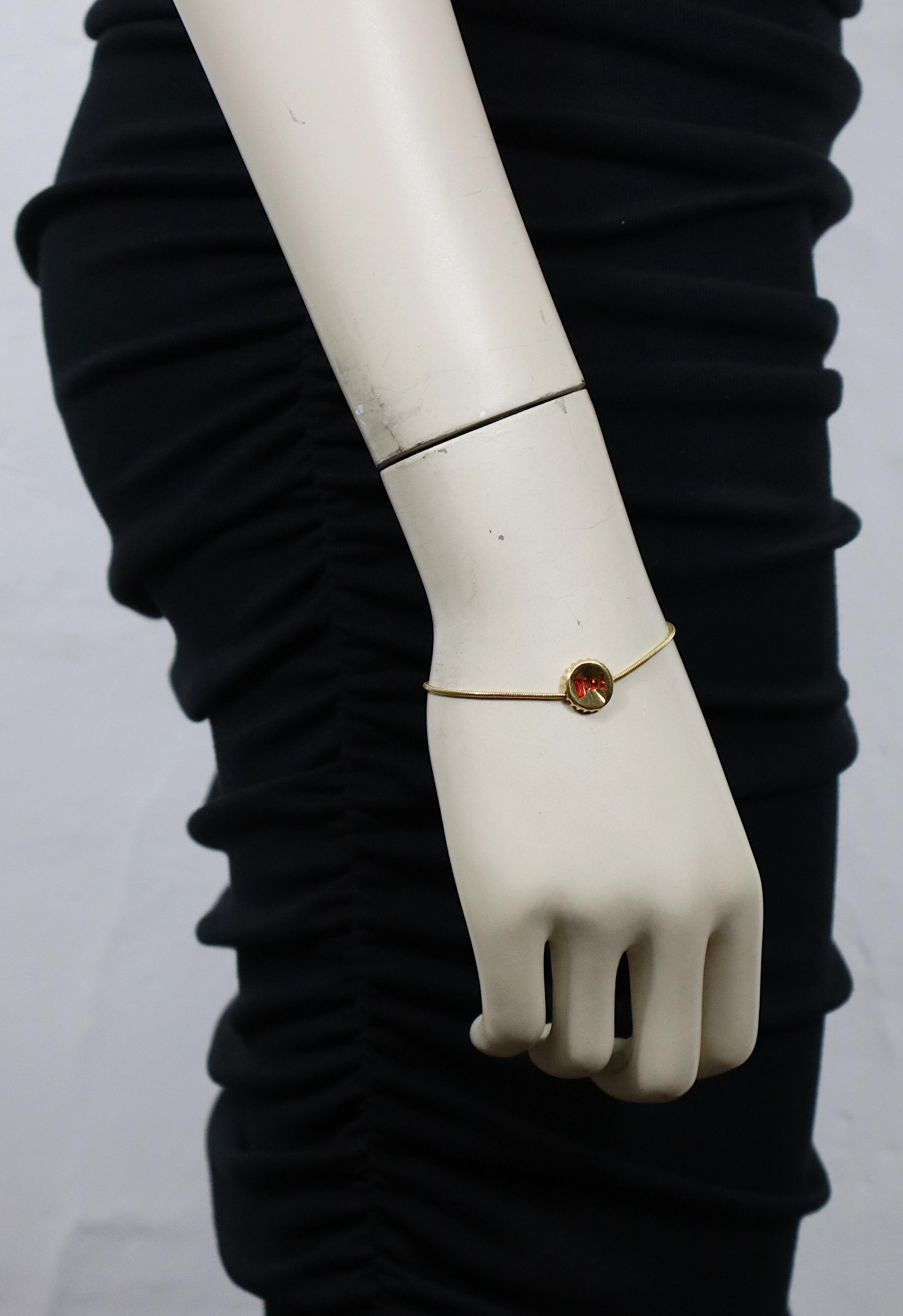 CHRISTIAN DIOR Vintage-Armband mit goldfarbenem, zerknittertem Flaschendeckel und geprägtem DIOR-Logo, das mit roter Emaille verziert ist.

Karabiner-Verschluss.

Geprägte DIOR.

Ungefähre Maße: Länge ca. 17 cm (6,69 Zoll) / Durchmesser des