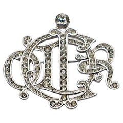 CHRISTIAN DIOR Broche vintage avec monogramme et logo, ornée de bijoux argentés