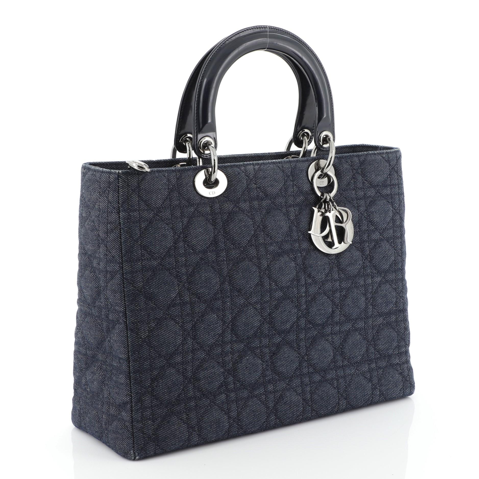 This Christian Dior Vintage Lady Dior Bag Cannage Quilt Denim Large, crafted from blue cannage quilted denim, features transparent double handles with sleek Dior charms, and gunmetal-tone hardware. Its top zip closure opens to a blue fabric-lined