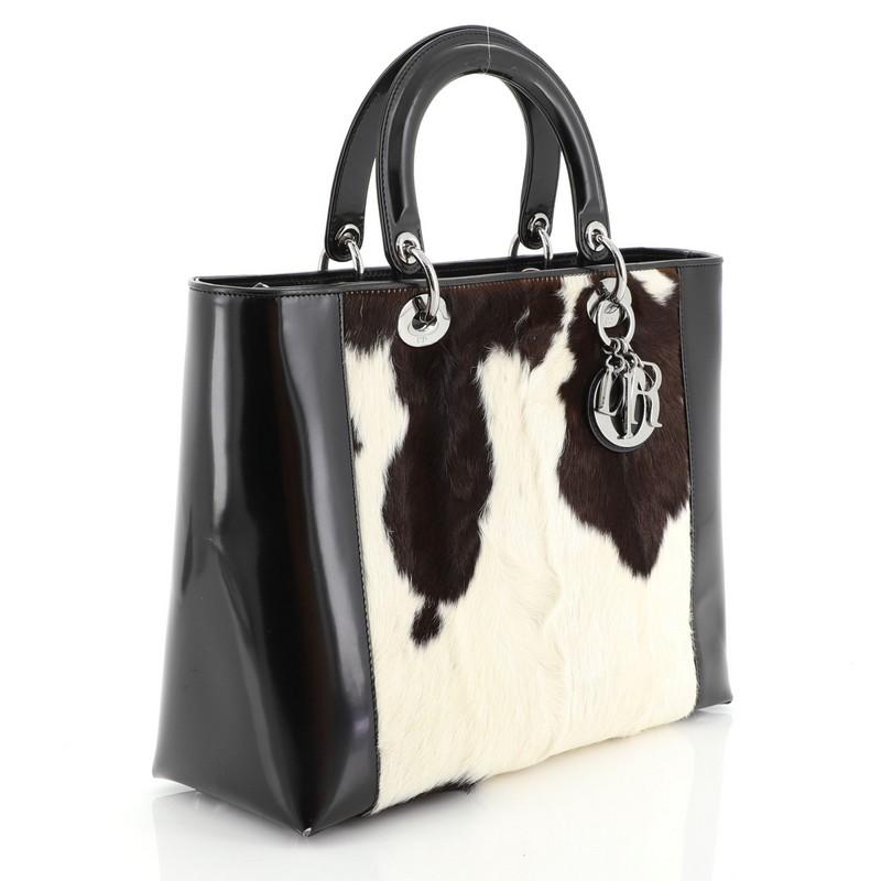 This Christian Dior Vintage Lady Dior Bag Pony Hair with Patent Large, crafted from black pony hair with patent leather, features dual short handles with Dior charms, protective base studs and silver-tone hardware. Its zip closure opens to a black