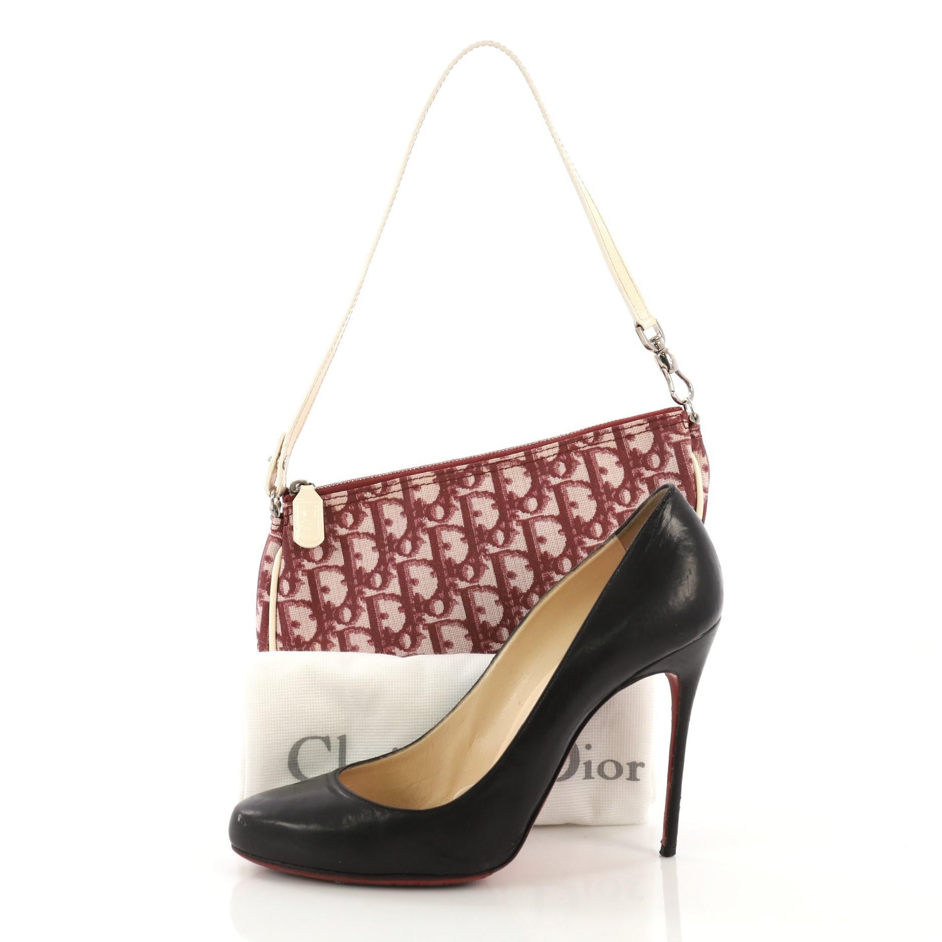 This Christian Dior Vintage Saddle Bag Diorissimo Canvas Mini, crafted from burgundy and white diorissimo canvas, features a top handle and aged silver-tone hardware. Its zip closure opens to a burgundy fabric interior. **Note: Shoe photographed is