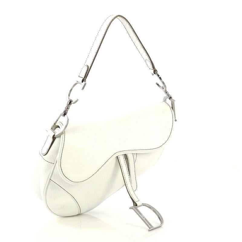 This Christian Dior Vintage Saddle Bag Leather Medium, crafted from white leather, features a top handle adorned with metal 'CD' finishing, saddle-shaped silhouette, and silver-tone hardware. Its fold over top opens to a brown fabric interior with