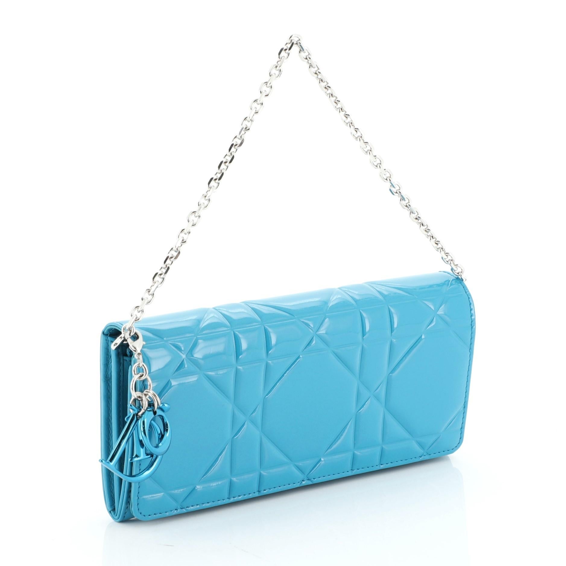 This Christian Dior Wallet on Chain Cannage Quilt Patent Small, crafted in blue patent leather, features cannage quilting and silver-tone hardware. It opens to a blue leather and fabric interior. 

Condition: Excellent. Faint scuffs on exterior,