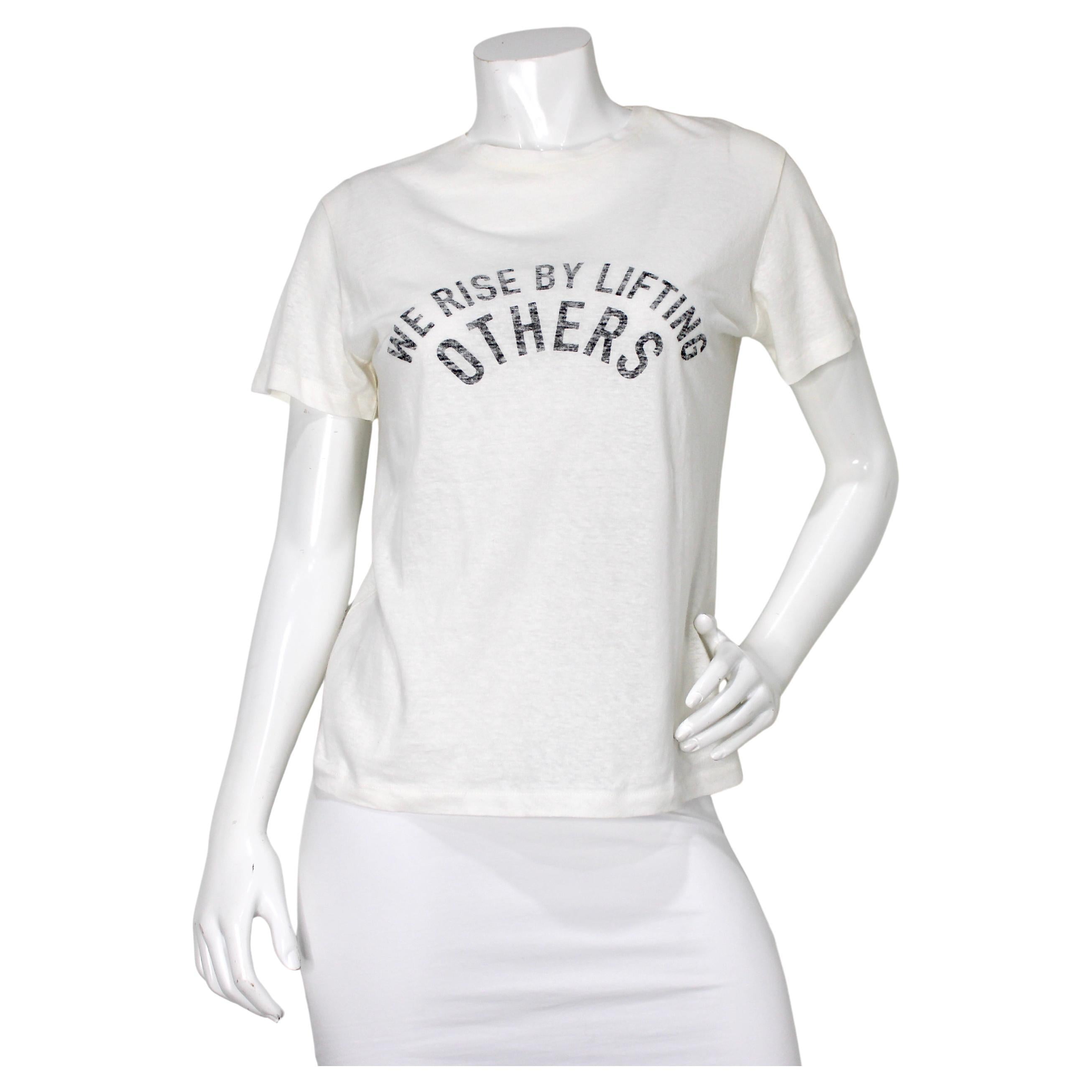 Camiseta cuello redondo Christian Dior "We Rise By Lifting Others" (Nos levantamos levantando a los demás) en venta