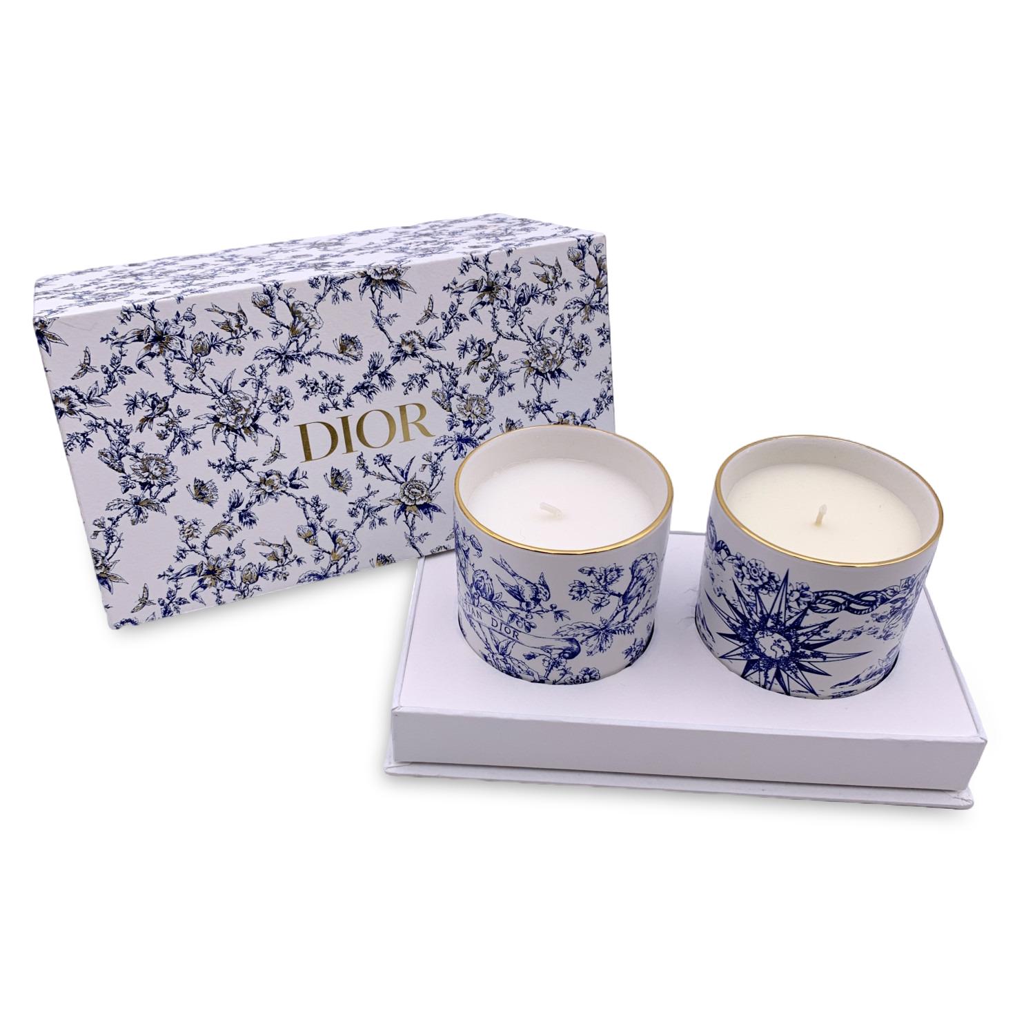 Beautiful Christian Dior mini scented candle set. The set consists of two porcelain candles with blue and white decorations, embellished with golden trim on top. Orange Canelle and Sapin Cypres scents. Made in France. Dimensions: 2.75 x 3 inches - 7