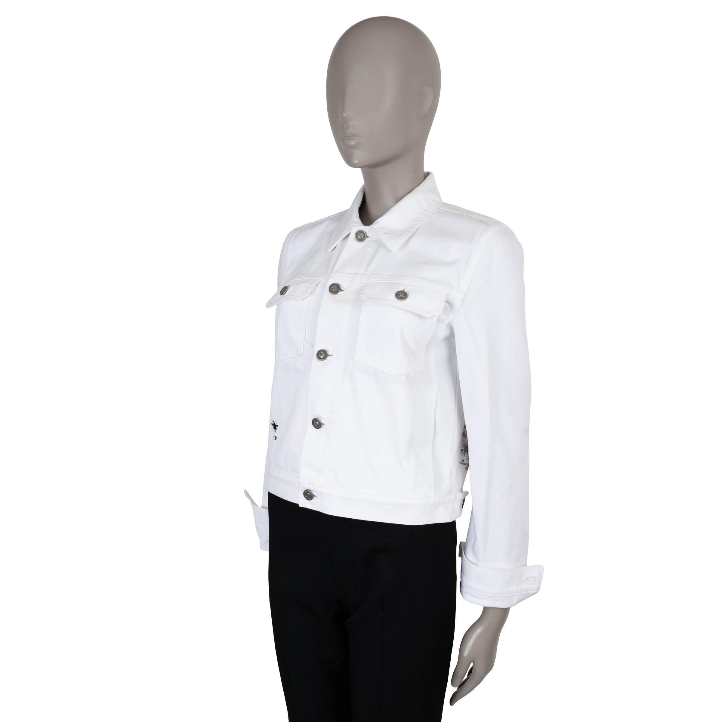 Cette veste en jean Christian Dior 100 % authentique en coton blanc (100 %) est une pièce remarquable ornée d'un imprimé multicolore vibrant d'étoiles et de faune indienne. Conçue avec une silhouette courte et carrée, elle présente un col pointu