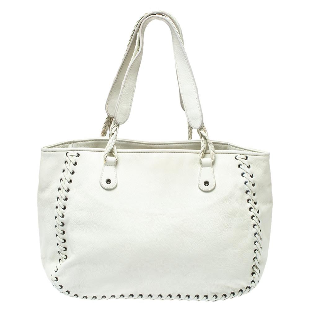 Crafted with leather and lined with fabric, you will find this stunning Dior tote an ideal companion for all your needs. It features whipstitch details on the exterior, dual handles, and a studded heart charm on the front. The interior is spacious