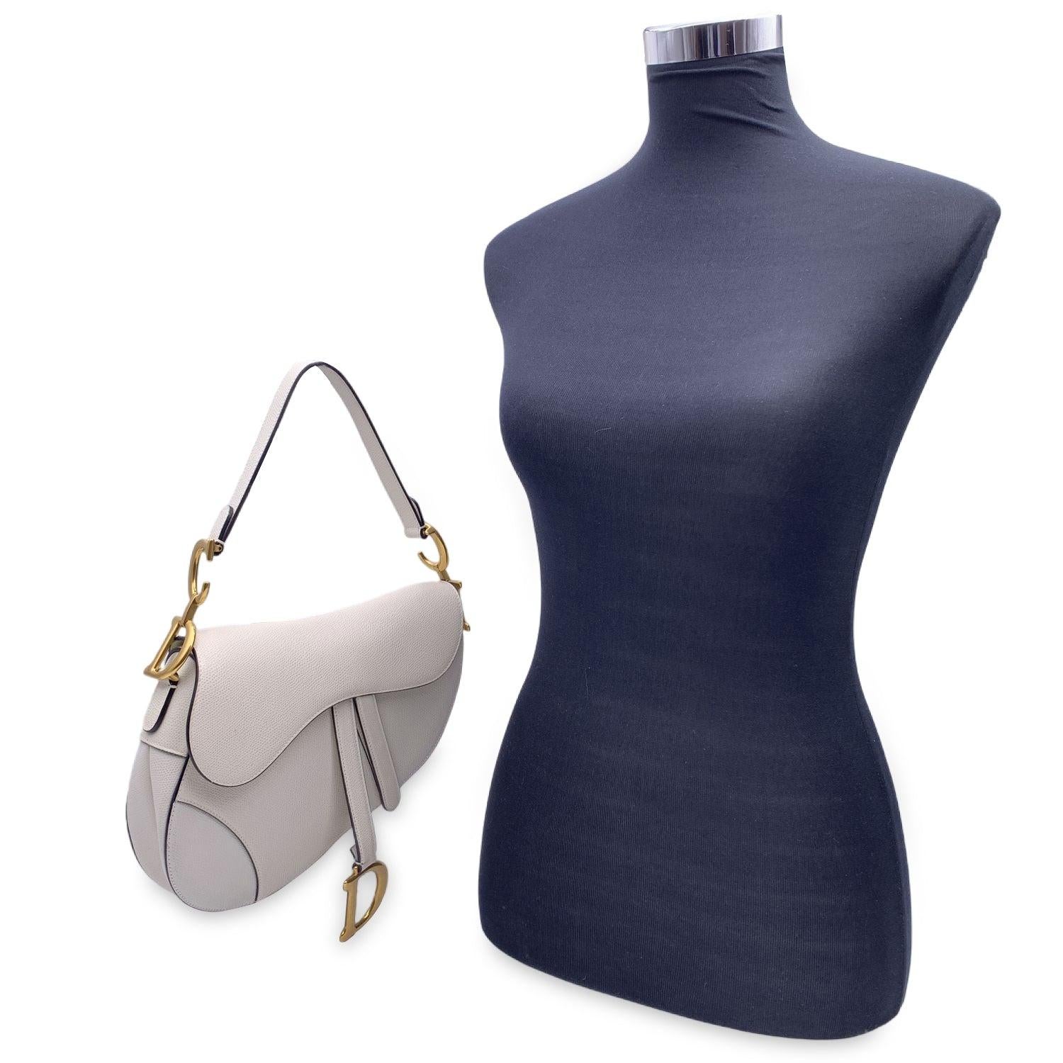 This beautiful Bag will come with a Certificate of Authenticity provided by Entrupy. The certificate will be provided at no further cost. Gorgeous CHRISTIAN DIOR Saddle Bag. This stylish shoulder bag is crafted in milk-colored grained calfskin, The