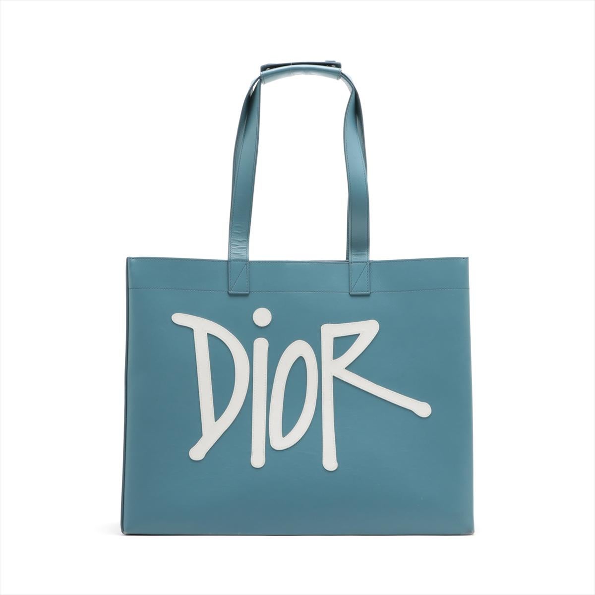 Le sac fourre-tout Christian Dior x Shawn Stussy Logo Leather Tote Bag in Blue est une collaboration unique et élégante qui fusionne les esthétiques emblématiques de Dior et de Shawn Stussy. Méticuleusement confectionné, ce sac fourre-tout présente