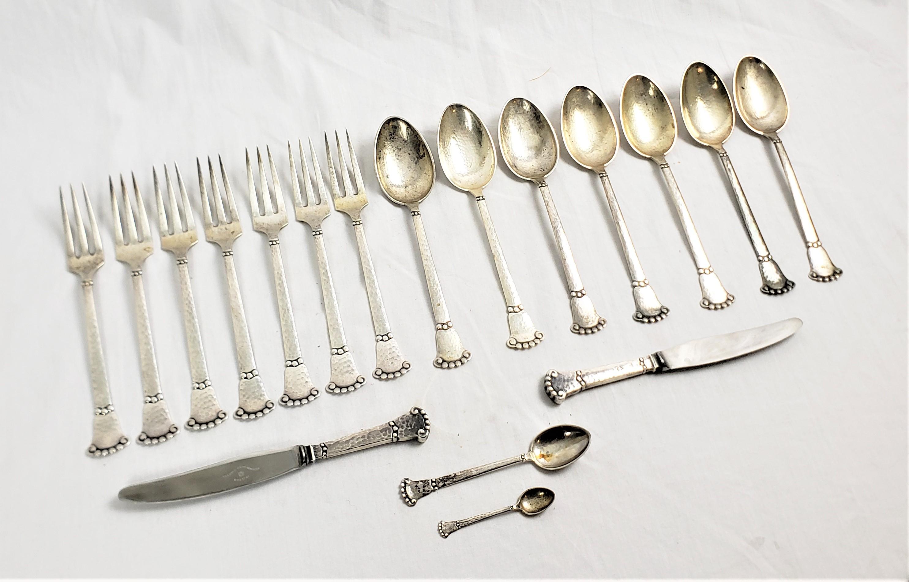 This eighteen piece set of flaware was made by the well known Christian F. Hiese of Denmark in approximately 1905 in the period Arts and Crafts style. This hand hammered set is composed of seven dinner forks, seven large soup spoons, two small