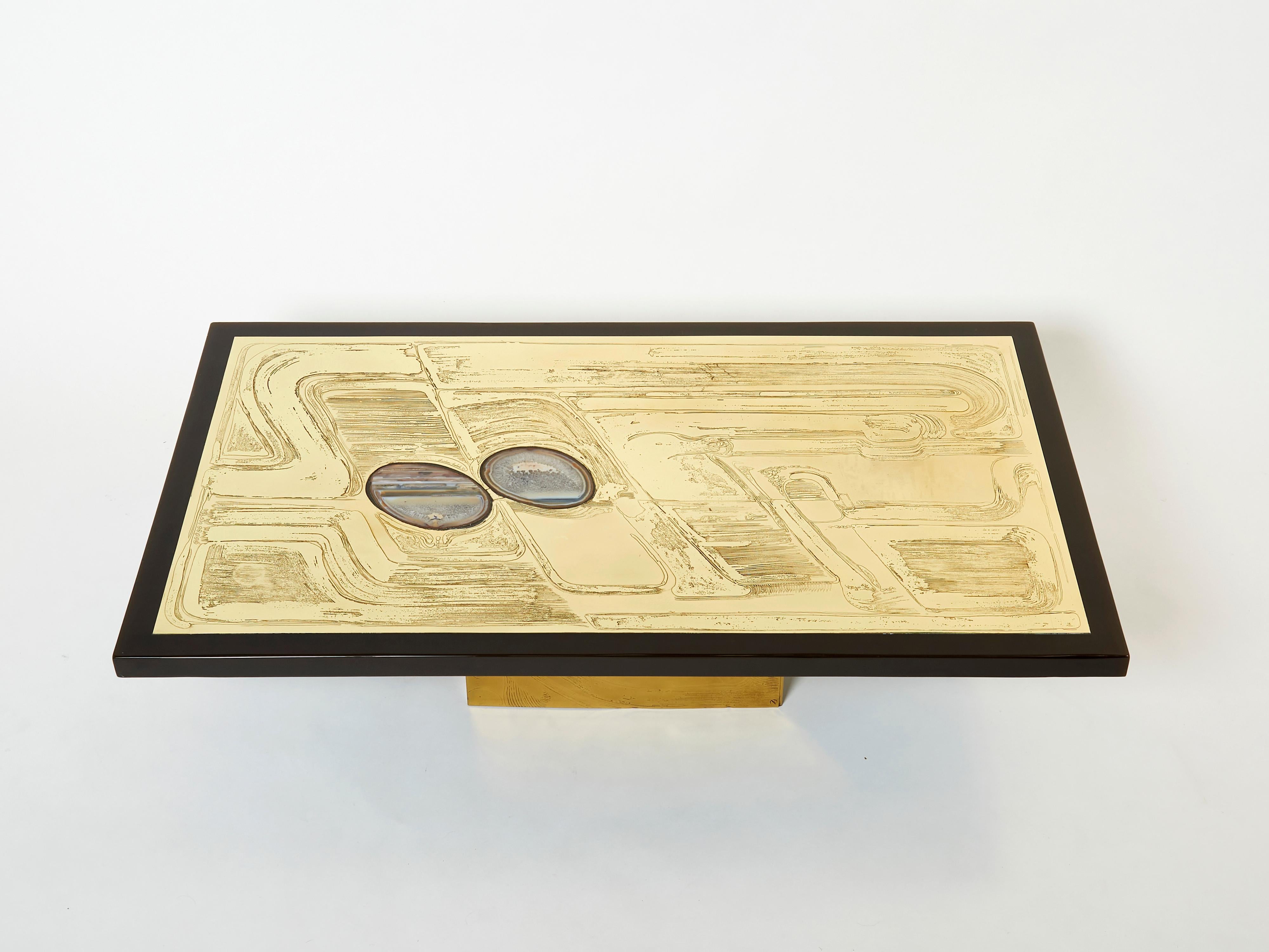 This is a beautiful Belgium coffee table signed by Christian Krekels in 1979. The table features a beautiful decorative etched brass table top, with two agate stones inlaid, framed by a dark brown resin insert. It is set on a large wood base,