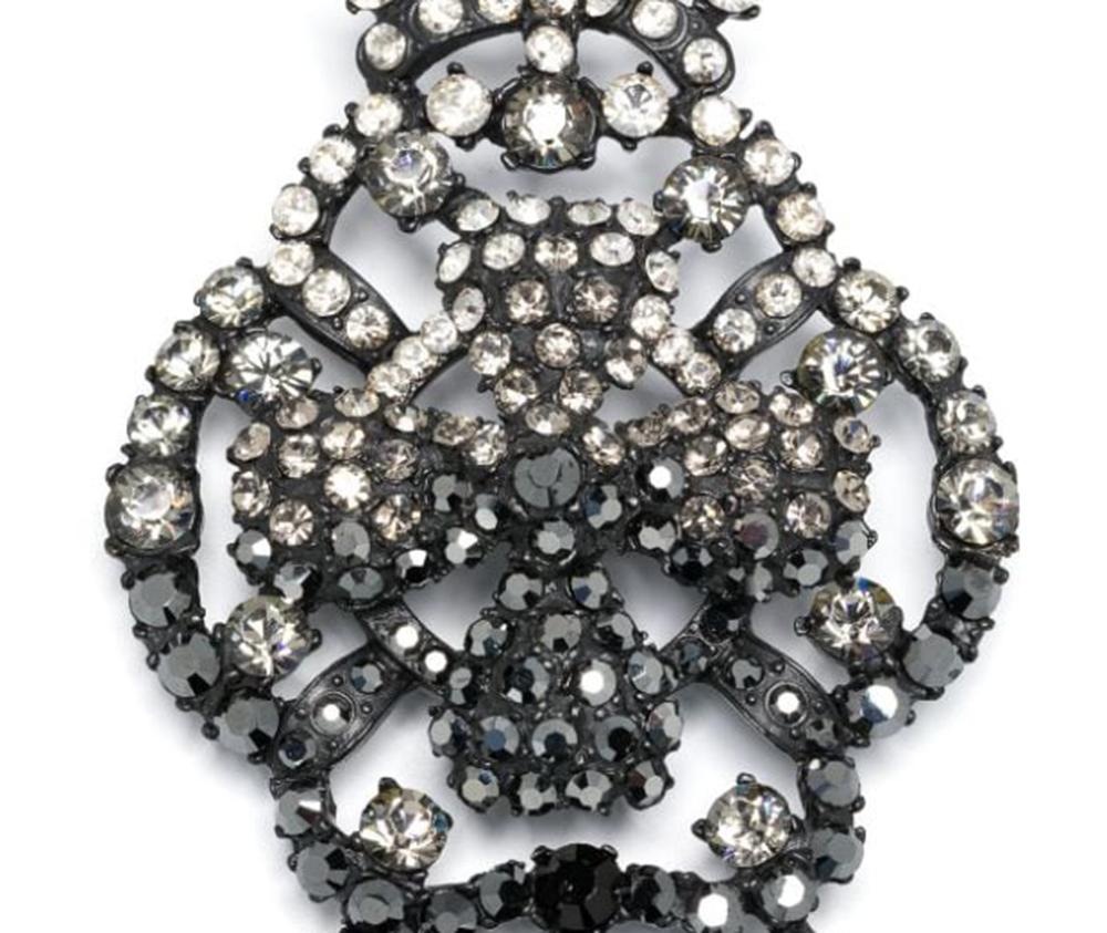 1990s Christian Lacroix rhinestone-embellished skull brooch featuring black metal with a design with a cross and skull motif, adorned with dazzling rhinestones in black and clear white tones, a back safety pin and a logo back plaque.
In good vintage