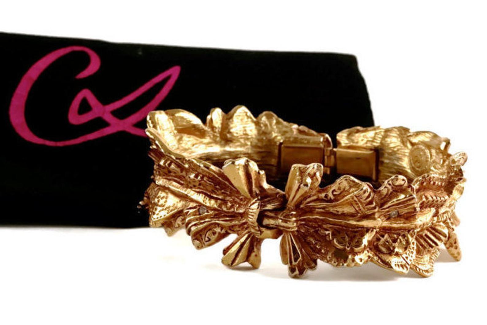 Vintage CHRISTIAN LACROIX Bow Ribbon Textured Lace Pattern Rhinestone Clamper Cuff Bracelet

Measurements:
Height: 1 inch (2.54 cm)
Inner Diameter: 6 4/8 inches (16.51 cm)

Features:
- 100% Authentic CHRISTIAN LACROIX.
- Textured bow/ ribbon in lace