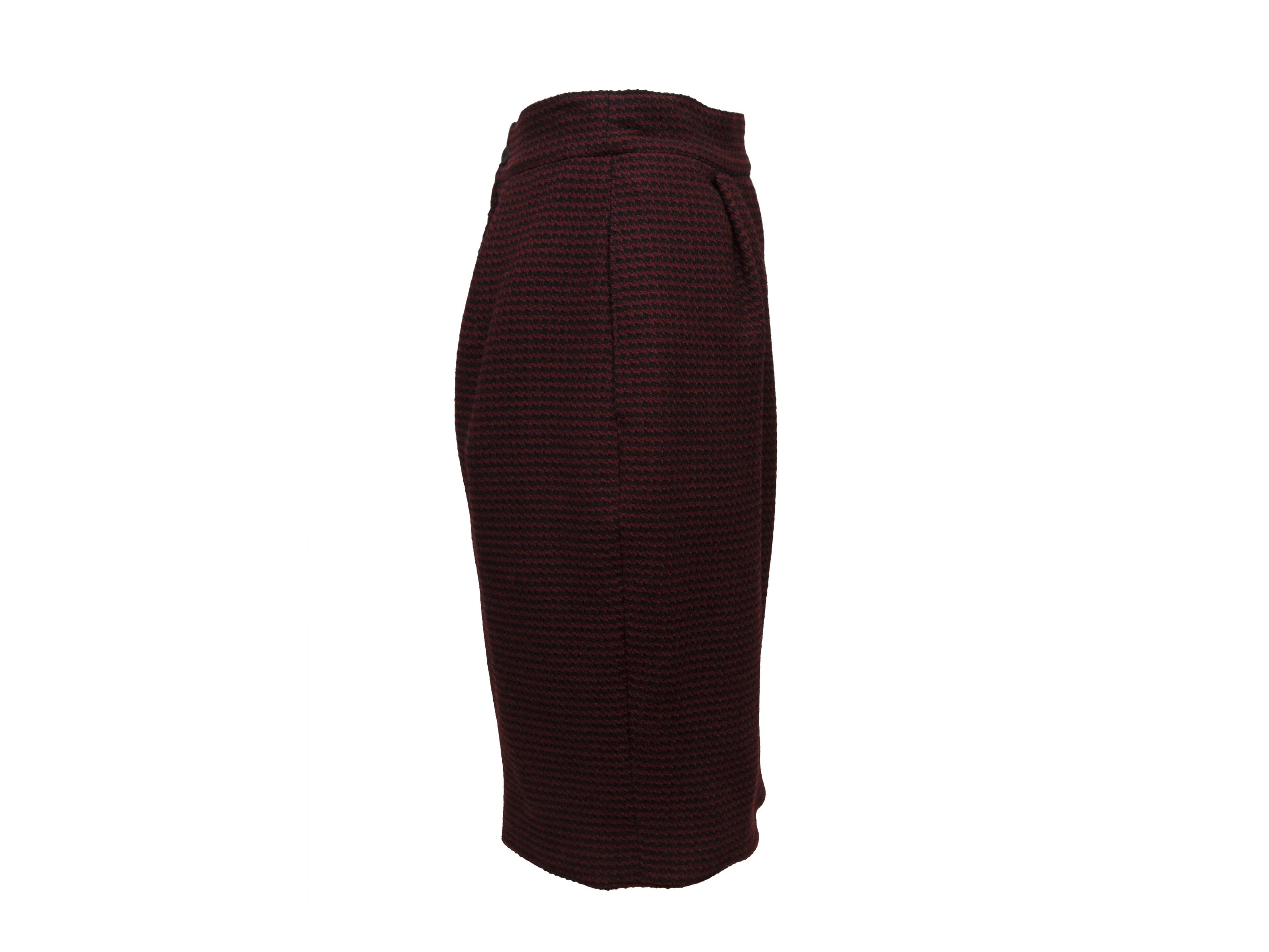 Product details: Burgundy and black wool skirt suit by Christian Lacroix. Houndstooth pattern throughout. Jacket features high neck, puff shoulders and zip closure at center front. Skirt features zip closure at back. Designer size 42. Jacket- 30