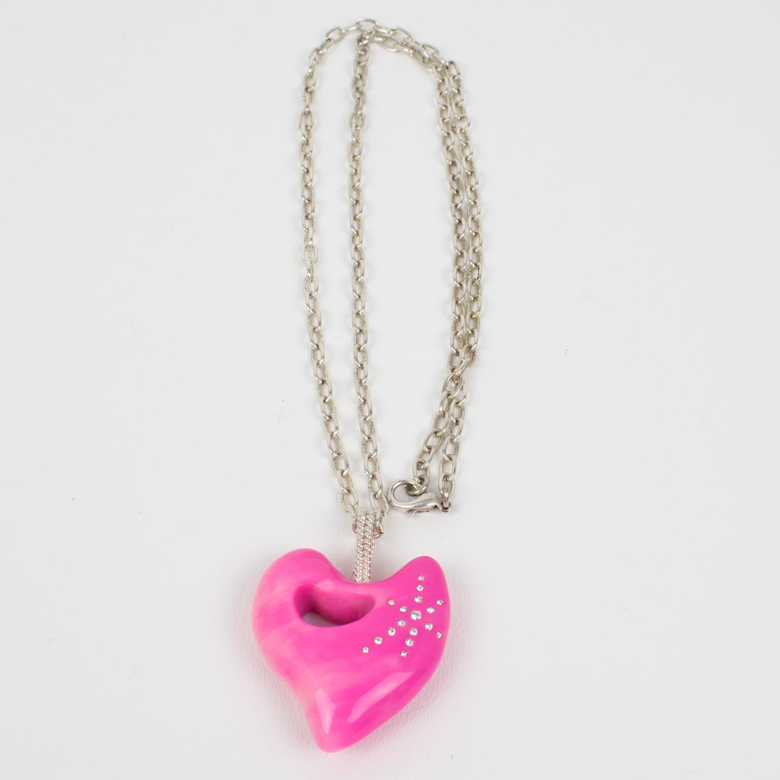 Questa splendida collana con ciondolo di Christian Lacroix a Paris presenta una lunga catena in argento, completata da un cuore dimensionale in resina ornato da strass di cristallo. Favoloso colore rosa caldo, tutto marmorizzato e con volute. Il