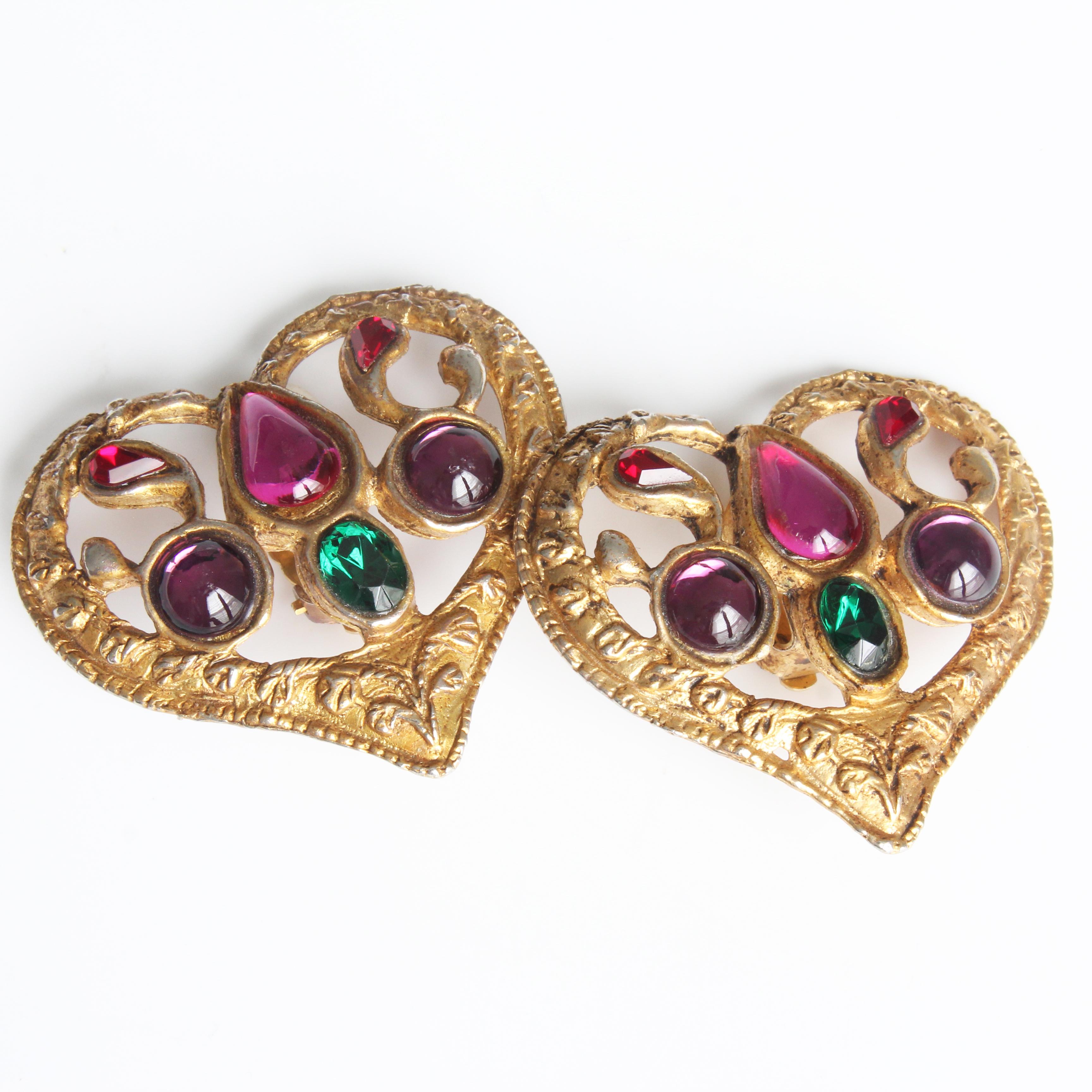 Preowned vintage and rare Christian Lacroix oversized heart-shaped earrings with colorful cabochons, likely made in the 90s.  Made from gold tone textured metal, these feature brilliant cabochons in shades of amethyst, pink, ruby red and emerald. 