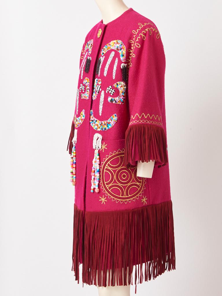 Christian Lacroix,  tono fucsia, sin cuello, lana, abrigo que tiene  un fleco de ante profundo en el dobladillo y el extremo de las mangas. El abrigo tiene grandes bolsillos de parche con bordados dorados. Libertine, recicló el abrigo  añadiendo