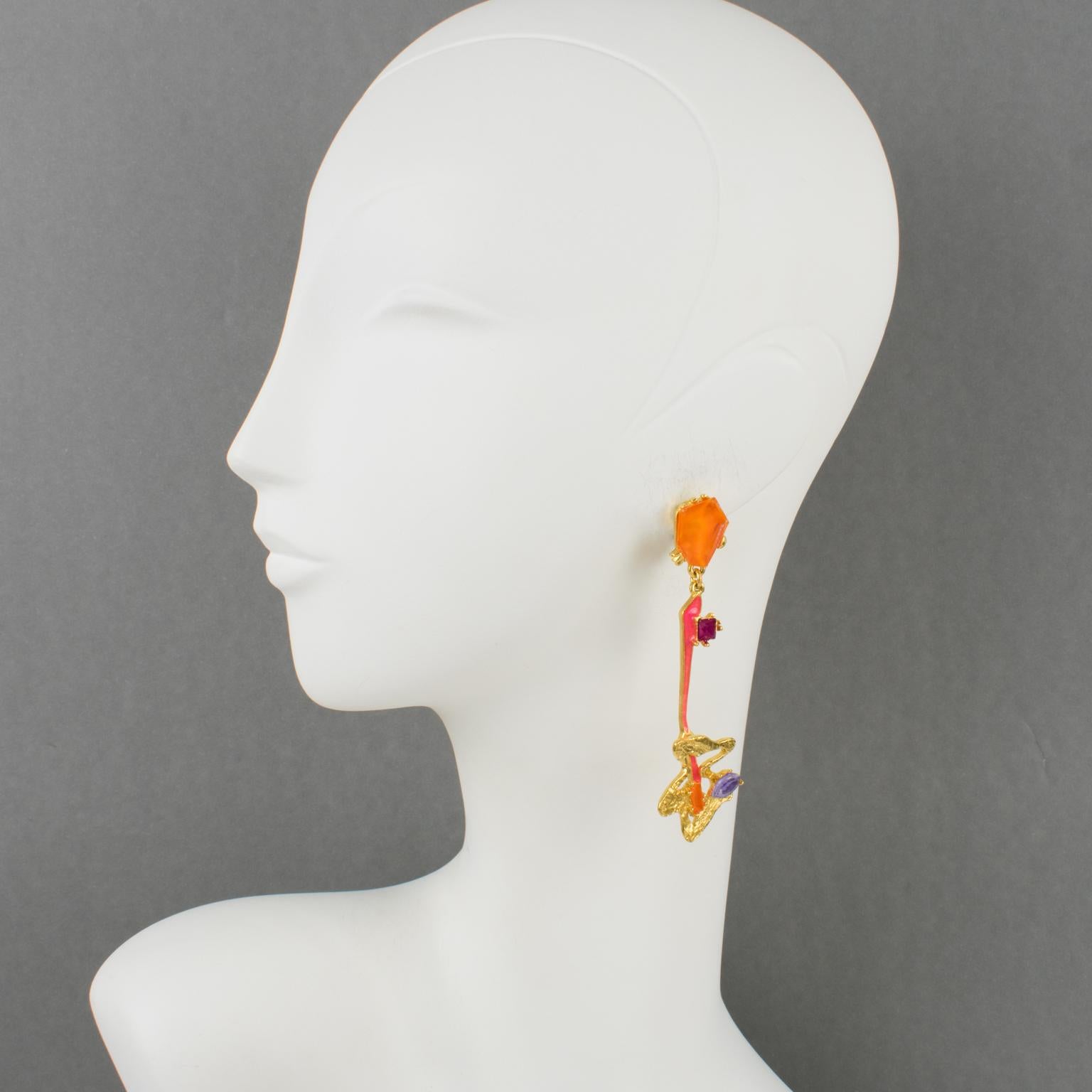 These gorgeous Christian Lacroix Paris futuristic clip-on earrings feature a textured gilt metal framing, complemented by a long dangling and articulated design, ornate with hot pink enamel and topped with orange, purple, and lavender crystal