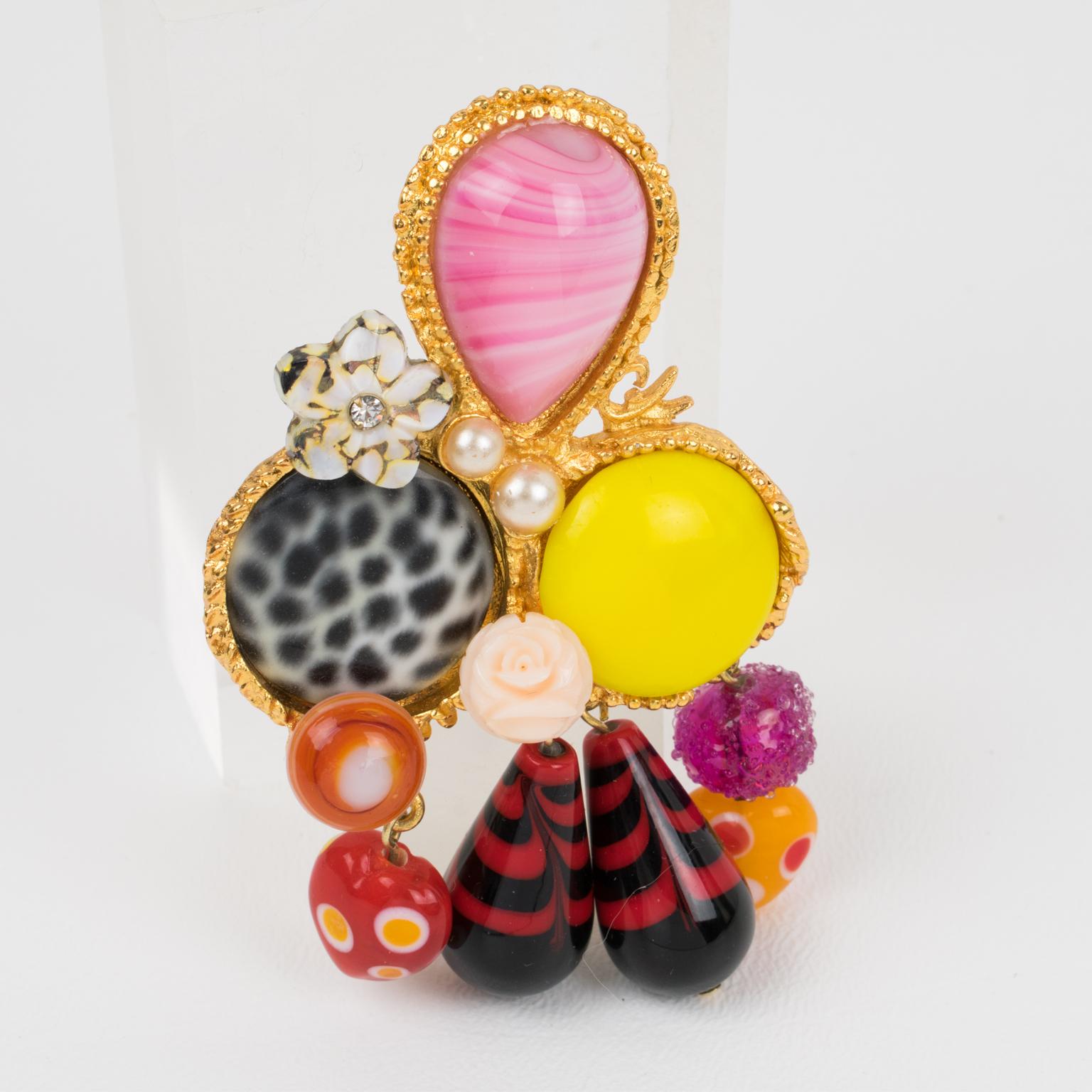 This mesmerizing Christian Lacroix Paris jeweled pin brooch features a geometric gilt metal framing with dangling charms, ornate with pearl-like, poured glass cabochons and pate de verre drop beads. The pin has superb assorted multicolor tones in