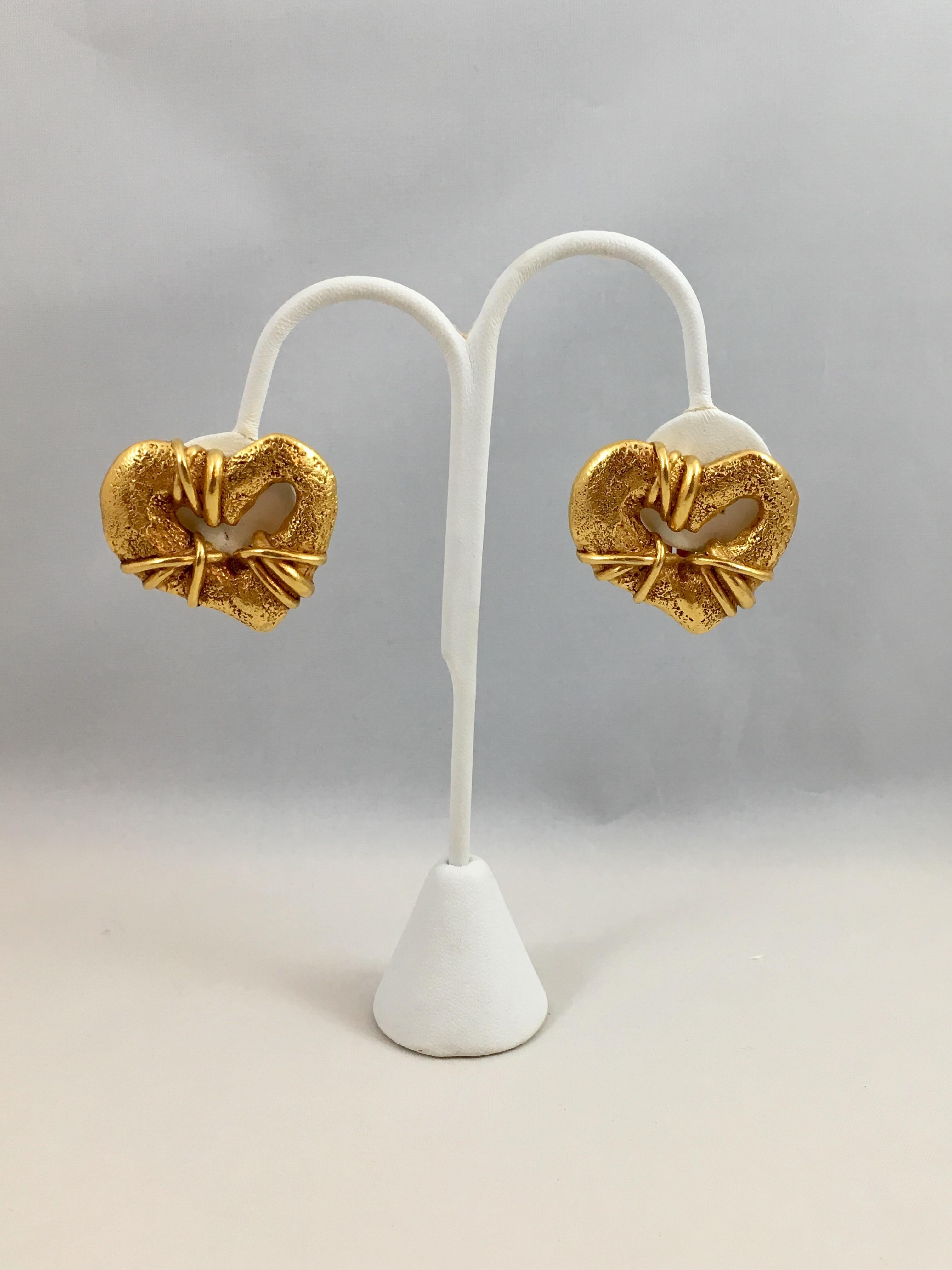 This is a pair of goldtone Christian LaCroix clip-on heart earrings. They measure 1 1/4 inches long x 1 3/16 inches wide. They are marked 'Christian LaCroix Made in France E 94' on the back. The E 94 stands for Ete 1994 or Summer 1994. They are in