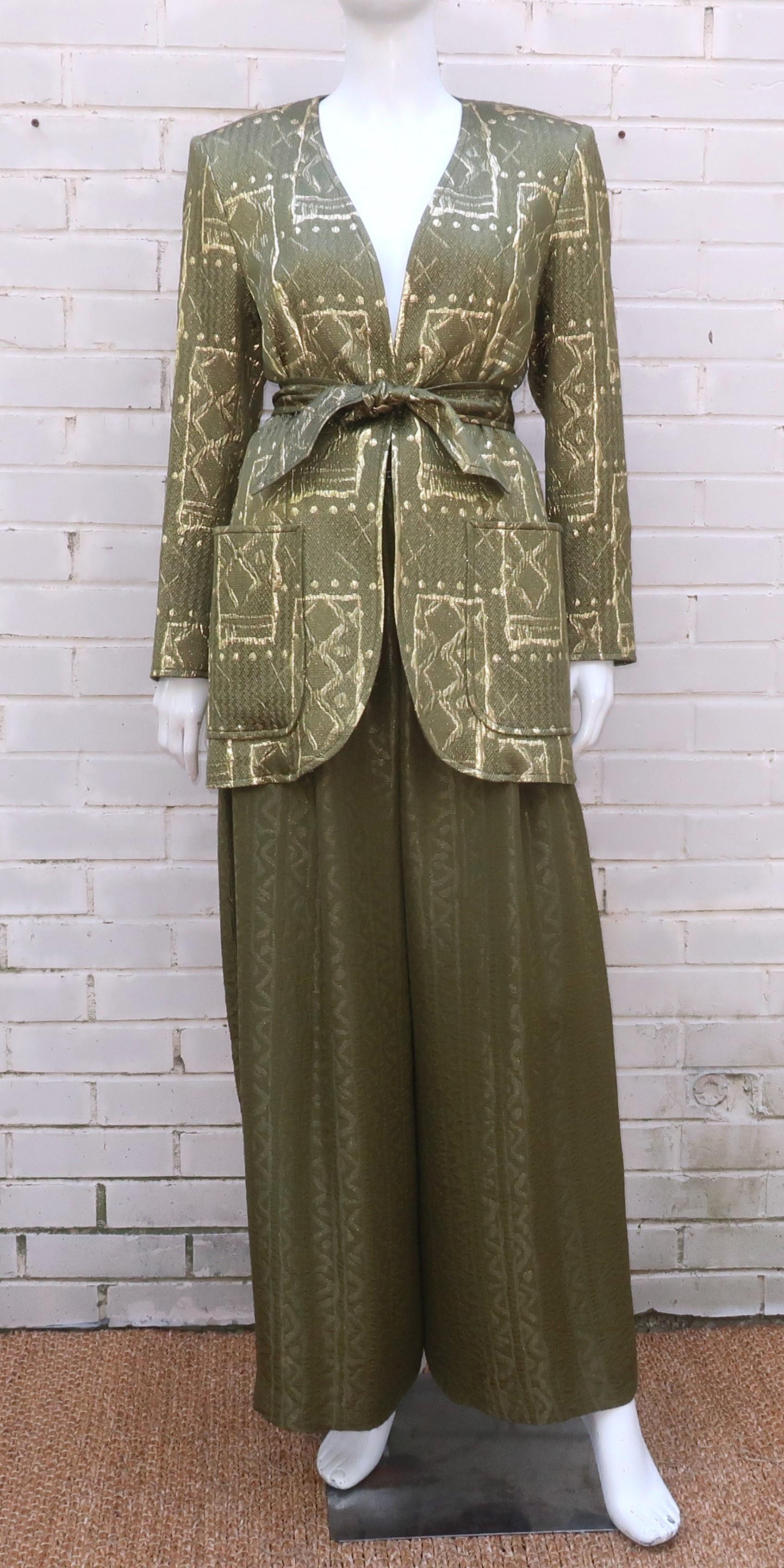 Opulento tailleur pantalone di Christian Lacroix composto da una giacca senza collo e pantaloni palazzo in tessuti di seta in misto oro e verde.  L'insieme ha un aspetto rilassato, simile a un pigiama da sera o a un abbigliamento da salotto.  La