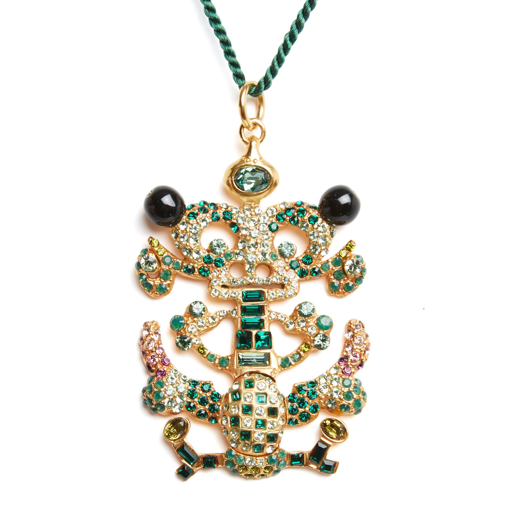 Christian Lacroix Pendentif XXL à motif d'une étrange créature en métal doré façonné, ajouré et incrusté de multiples strass principalement dans les tons de vert, de toutes formes et tailles, large anneau pour retenir l'ensemble, monté sur un cordon