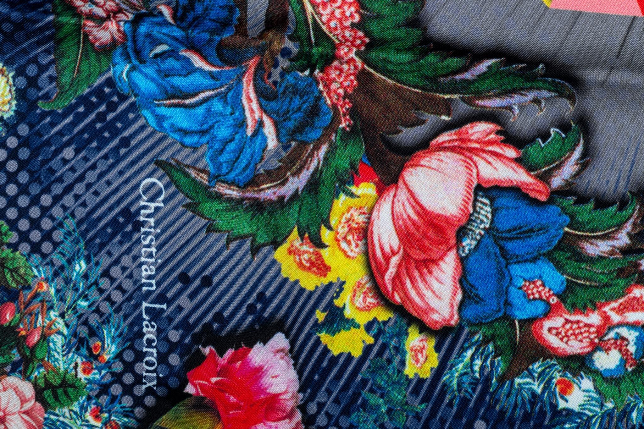 Petit foulard vintage 100% soie de Christian Lacroix en état neuf. Fond bleu avec motif multicolore.