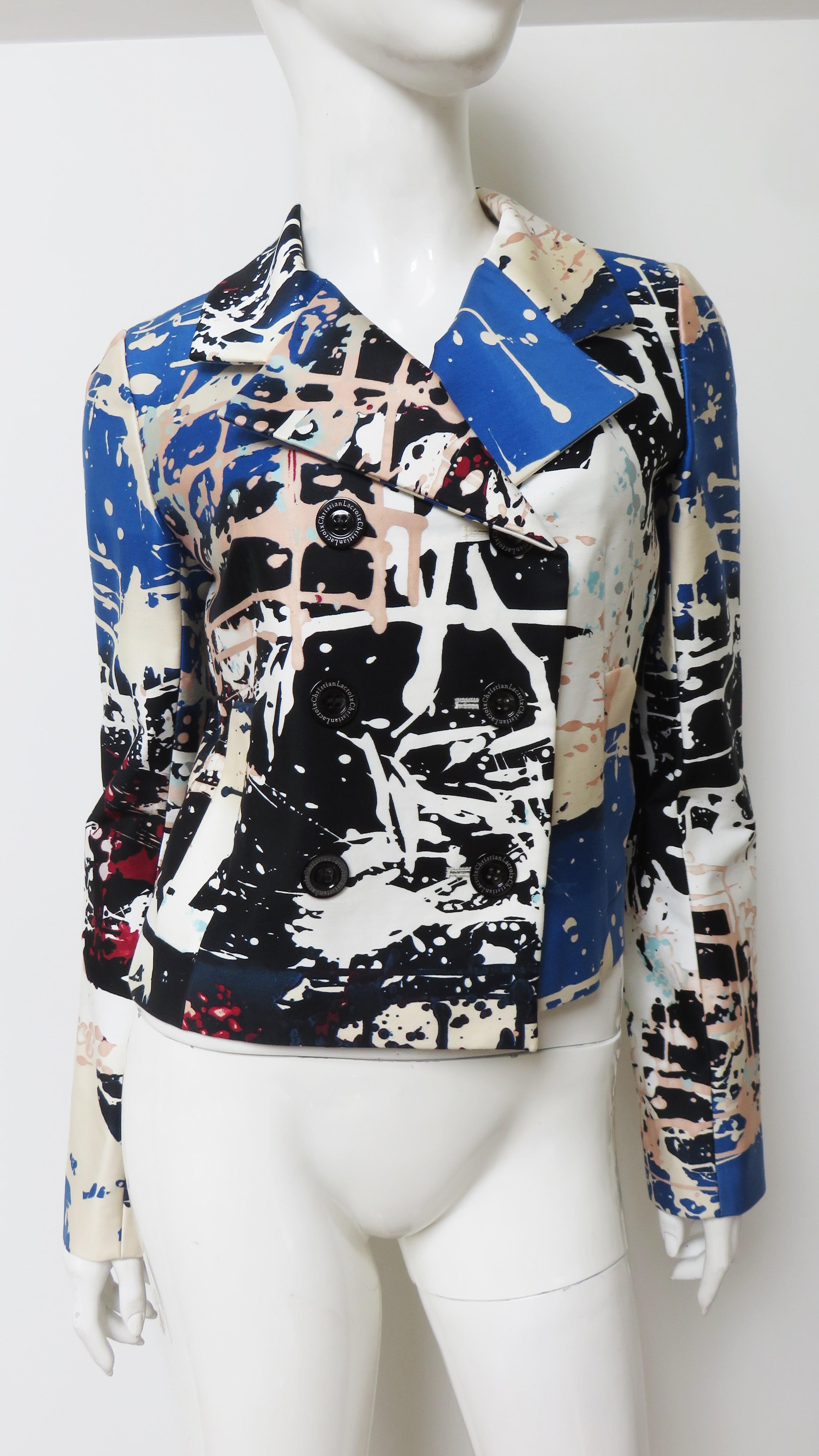 Giacca in cotone lucido con stampa grafica a schizzi di vernice di Christian Lacroix in blu, bianco, beige e blush.  È a doppio petto con bottoni neri, colletto a bavero e foderato in seta nera a pois bianchi.
Adatto alle taglie Small e Medium. 
