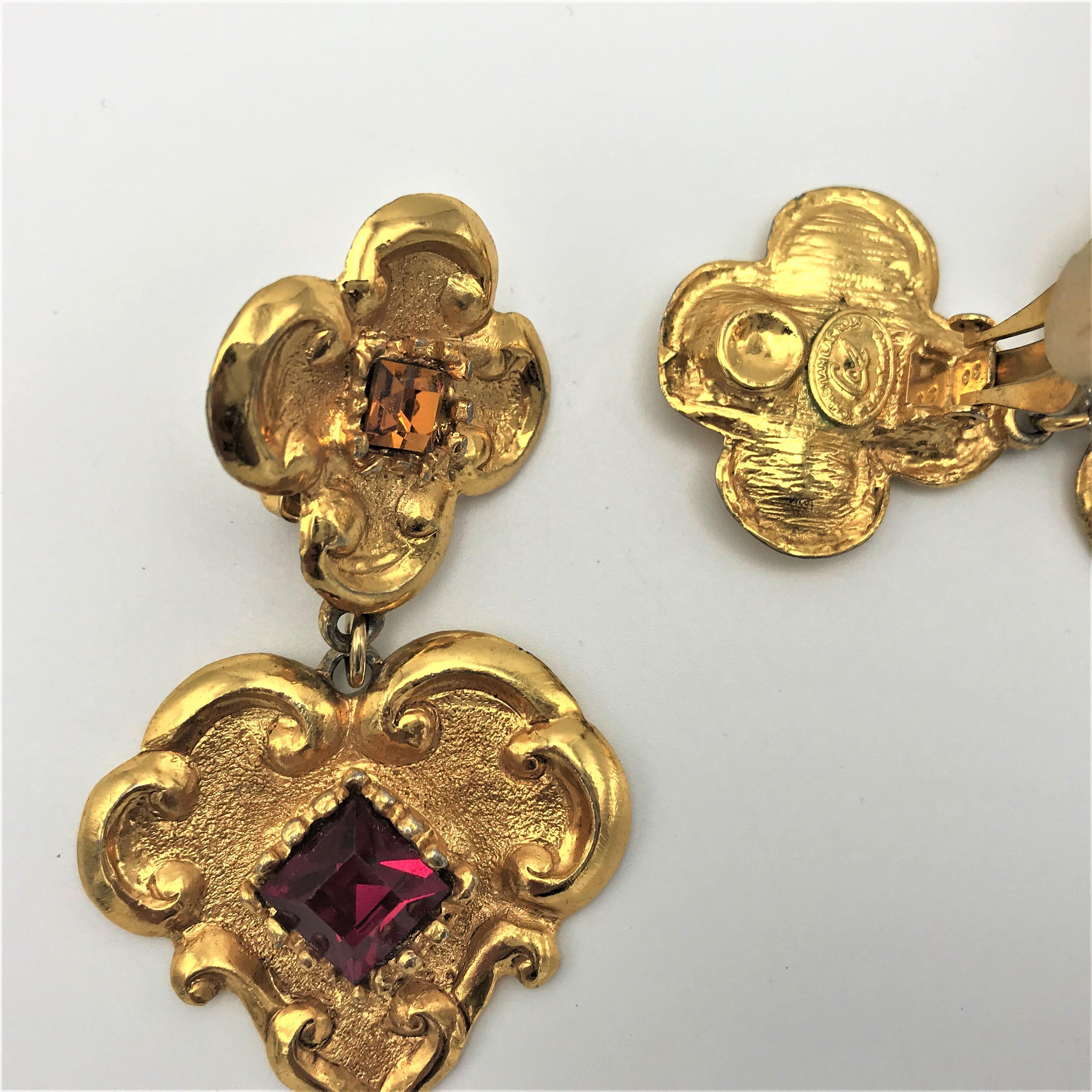 An attractive ear clip from Christian Lacroix Paris around the 1980s gold plated. 
The upper part in the shape of a 4-petalled flower with gold-colored square Strass stone. Attached to it a baroque heart with square red cut rhinestone. Signed on the