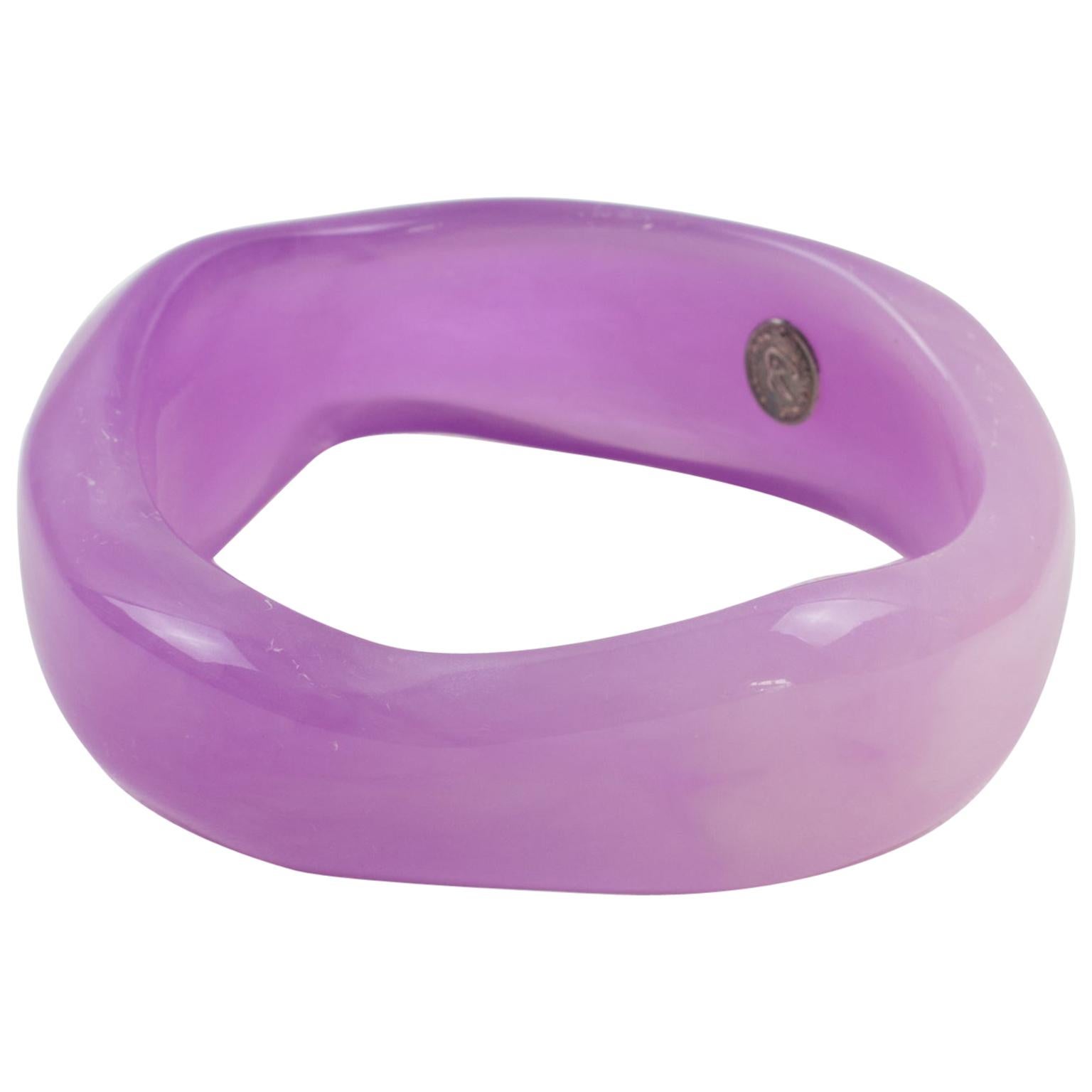 This stunning Christian Lacroix Paris Space Age Resin or Lucite bangle bracelet features a chunky free-form design in purple lavender color with swirling. The bangle is signed inside with a silvered metal tag logo reading Christian Lacroix - CL -