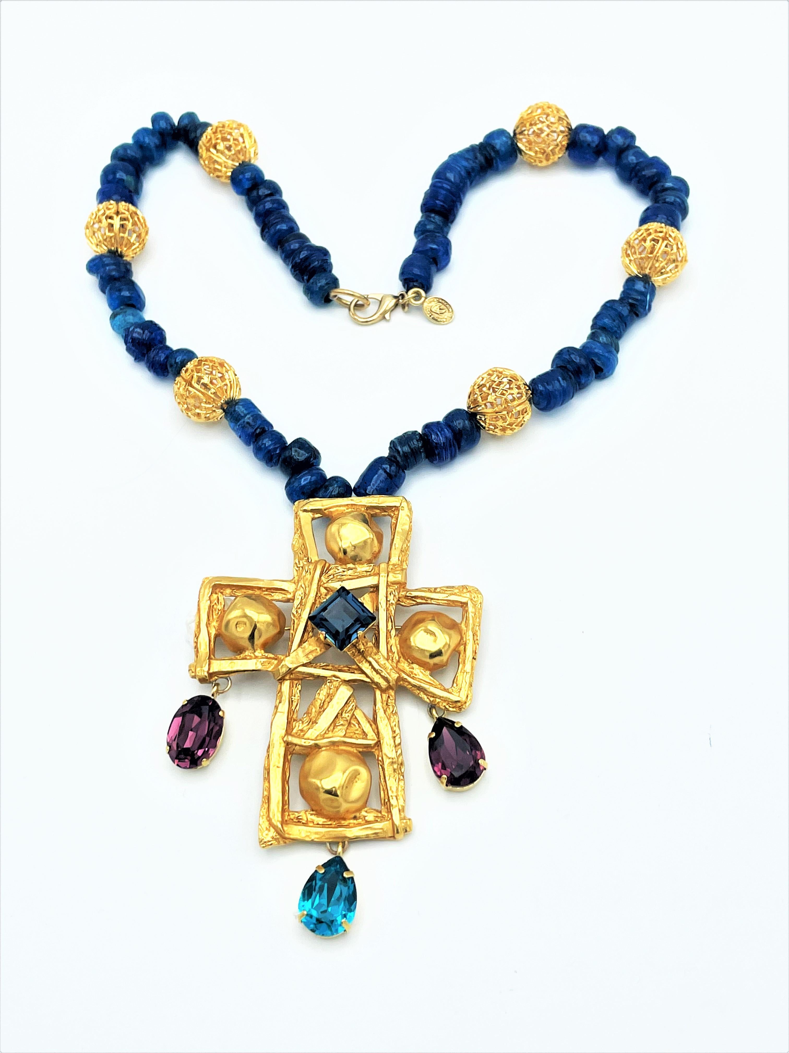 Broche en forma de cruz con adornos de brillantes colgando de una cadena azul con bolas doradas de Christian Lacroix Paris, hacia 1980-.
El broche en forma de cruz sin pedrería se vende por separado por 750 euros

Dimensiones; 
La longitud total de