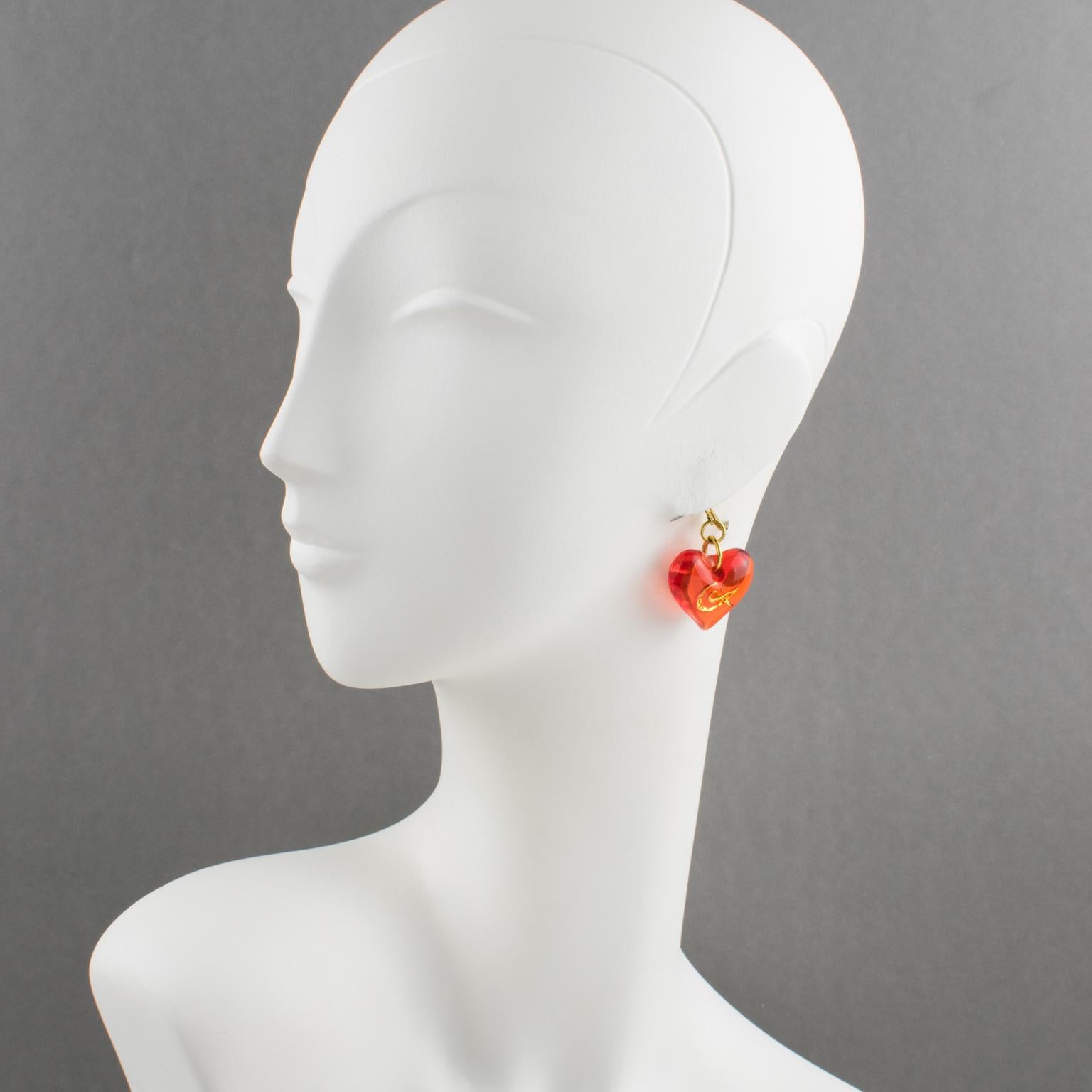 These lovely Christian Lacroix Paris pierced resin earrings feature a dimensional dangling heart shape in transparent neon orange color embellished with a gilt metal 
