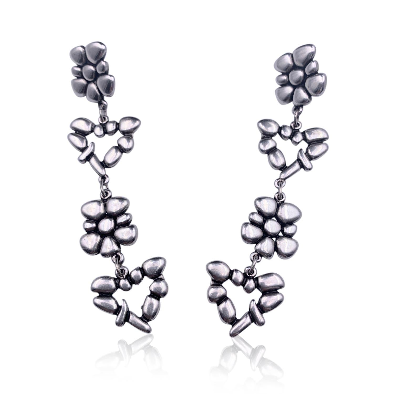 Beautiful earrings by Christian Lacroix, from the love story line. Made in silver-tone metal with hearts and flowers pendant. For pierced ears. Length: 4 inches - 10.2 cm. 'Christian Lacroix Paris' signature engraved on the reverse of the