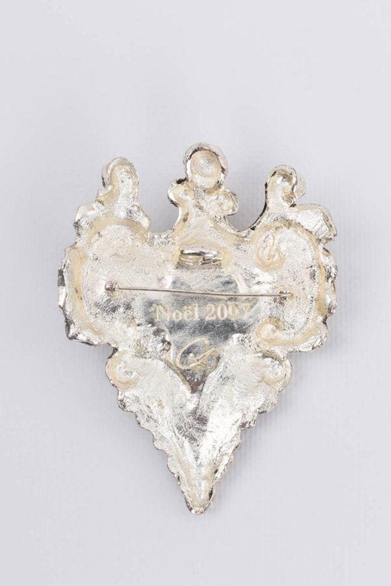 Christian Lacroix - Broche en métal argenté en forme de médaillon avec un petit miroir. 

Informations complémentaires :
Dimensions : 10 cm x 8 cm (3,93