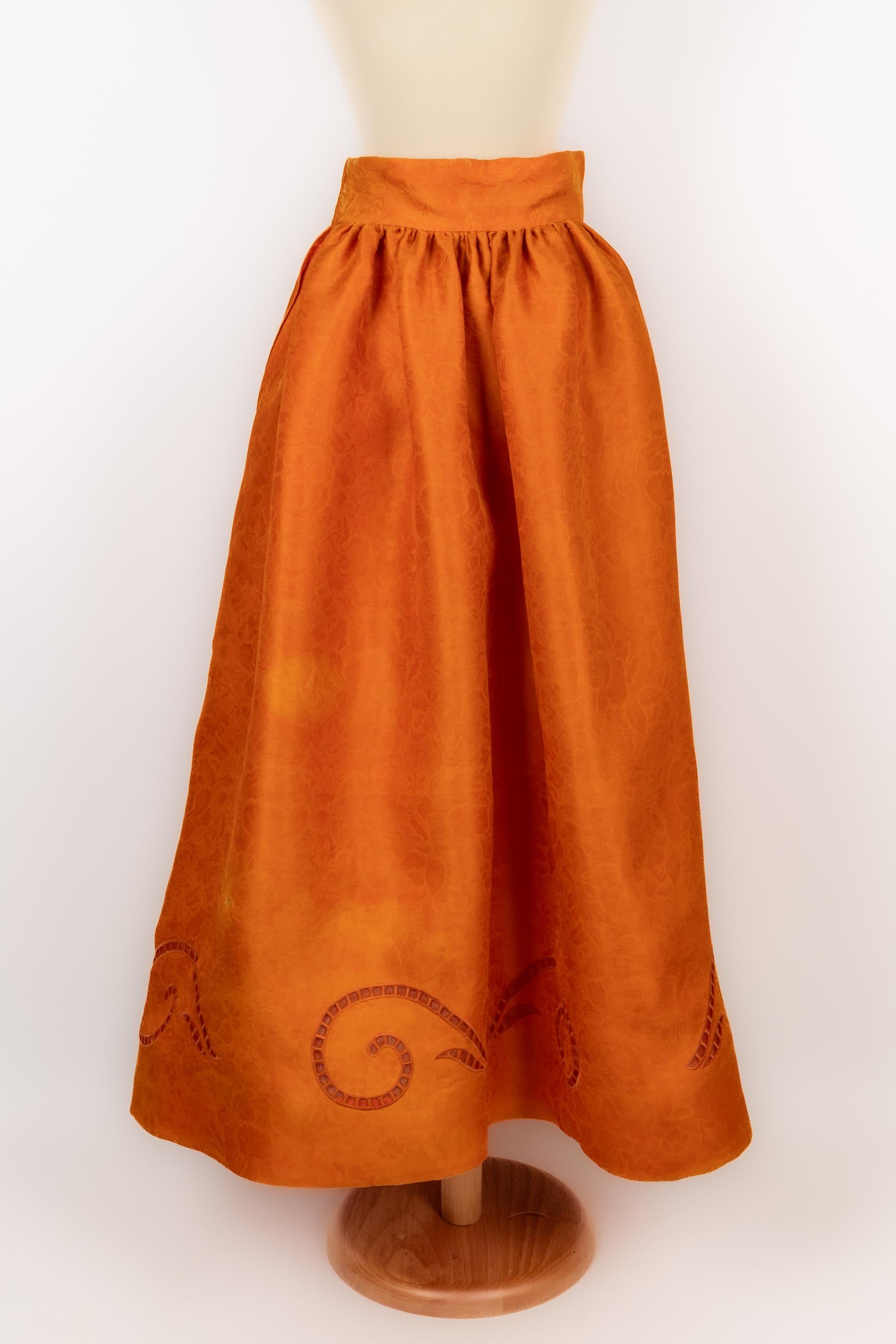 CHRISTIAN LACROIX - Longue jupe en organza orange à motif de fleurs de même ton, broderie anglaise et point plat. Aucune taille n'est indiquée, il convient à un 36FR. Collectional 1990/1992. A signaler, quelques marques blanches et marques