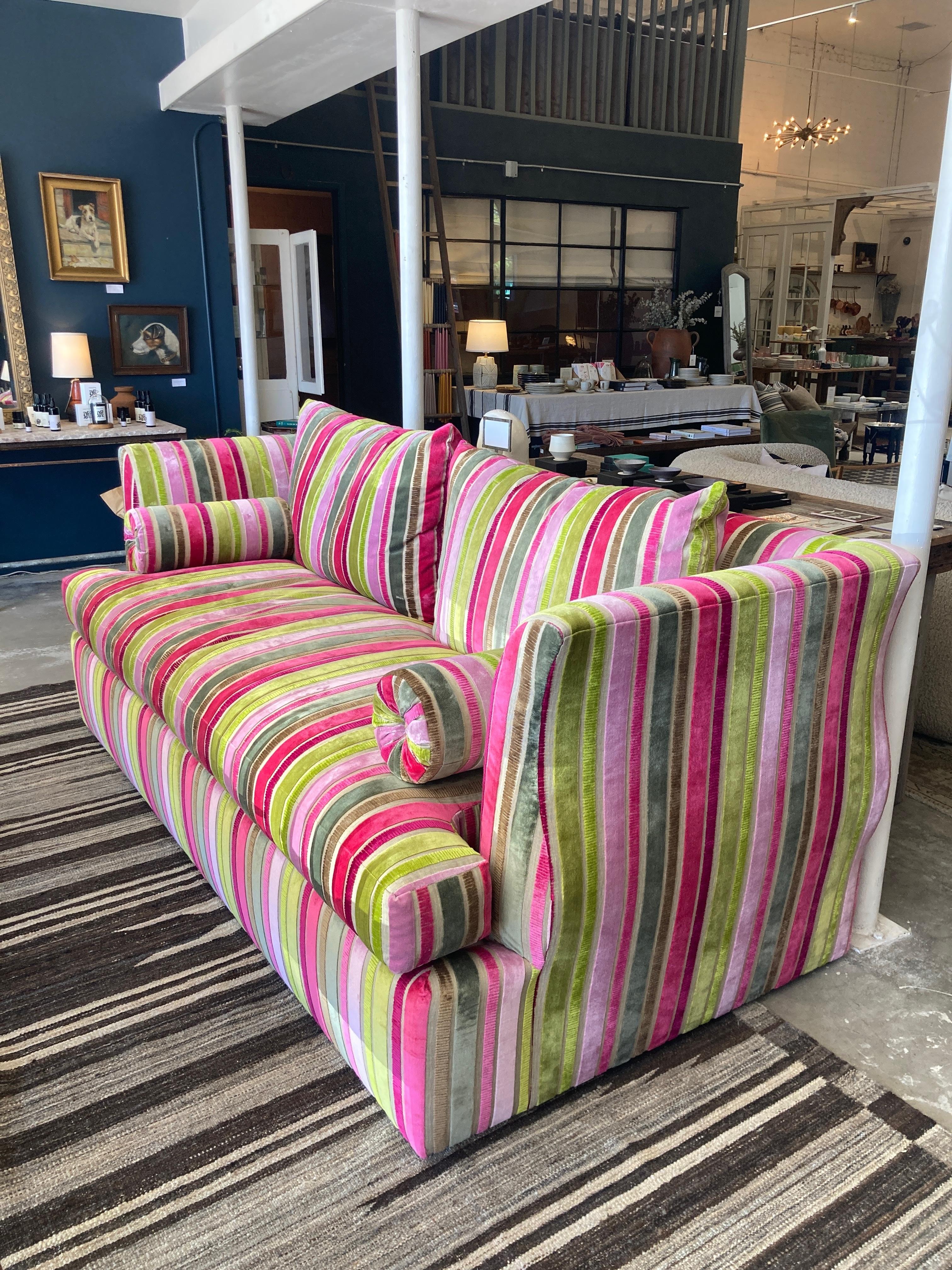 This remarkable sofa, upholstered in sumptuous Christian Lacroix striped velvet, is a stunning example of couture-inspired interior design. The vivid interplay of fuchsia, lime, rose, silver, and taupe stripes exudes a sense of theatrical elegance —