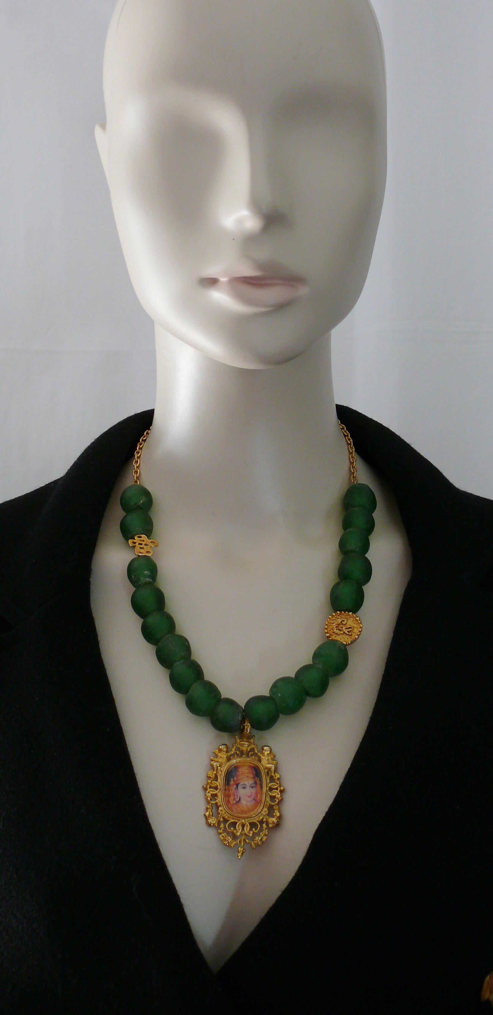 CHRISTIAN LACROIX vintage necklace made of antique like green glass frosted beads featuring an Hindu deity printed portrait in a gold toned baroque medallion, a cross and CL monogram textured coin.

T bar and toggle closure.

Embossed CHRISTIAN