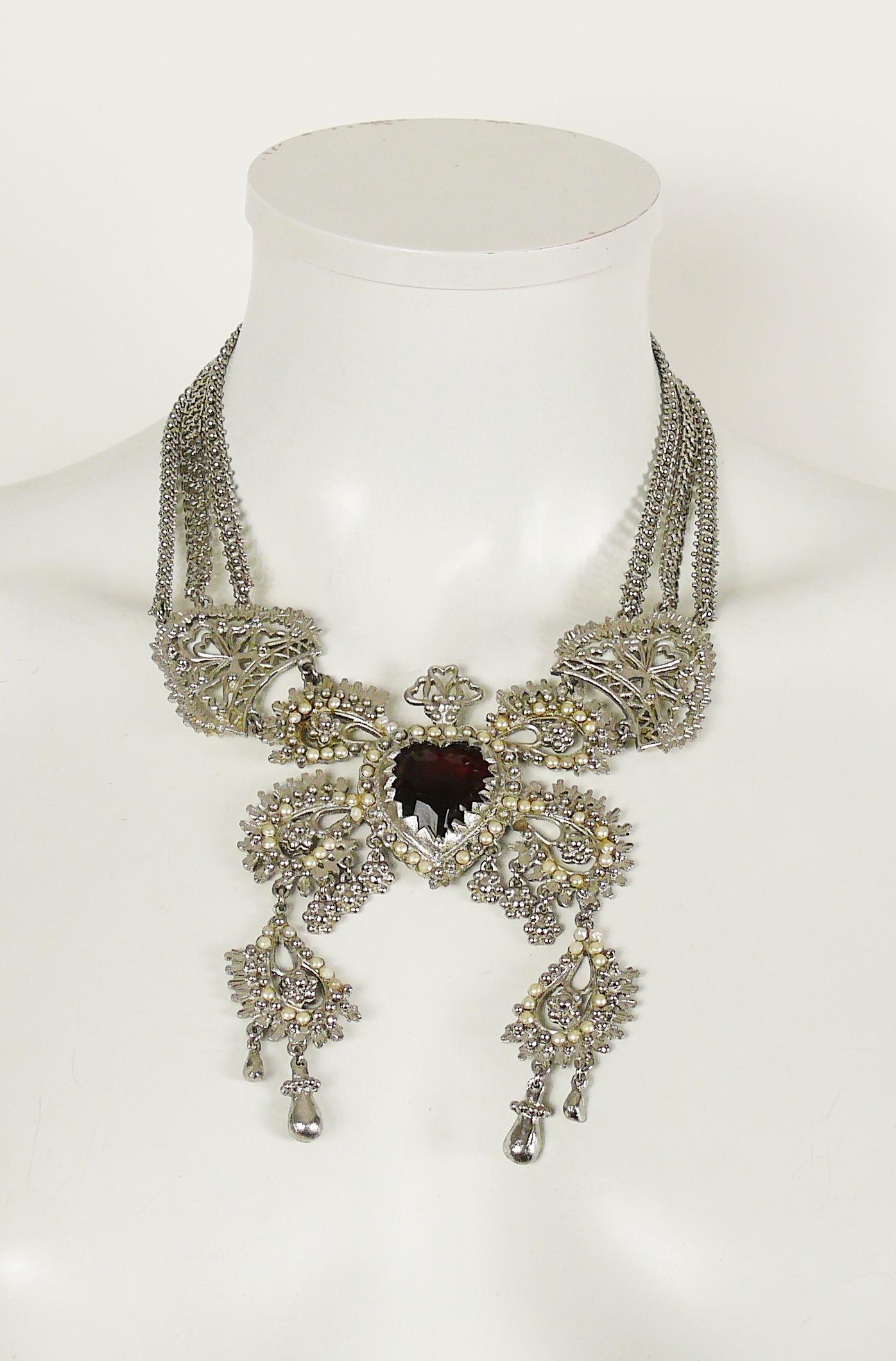 CHRISTIAN LACROIX vintage rare and opulent multi chain silver toned necklace featuring an ex voto sacred heart, adorned with boteh-like design details, embellished with a large faceted ruby glass cabochon and off-white pearls.

Hook clasp
