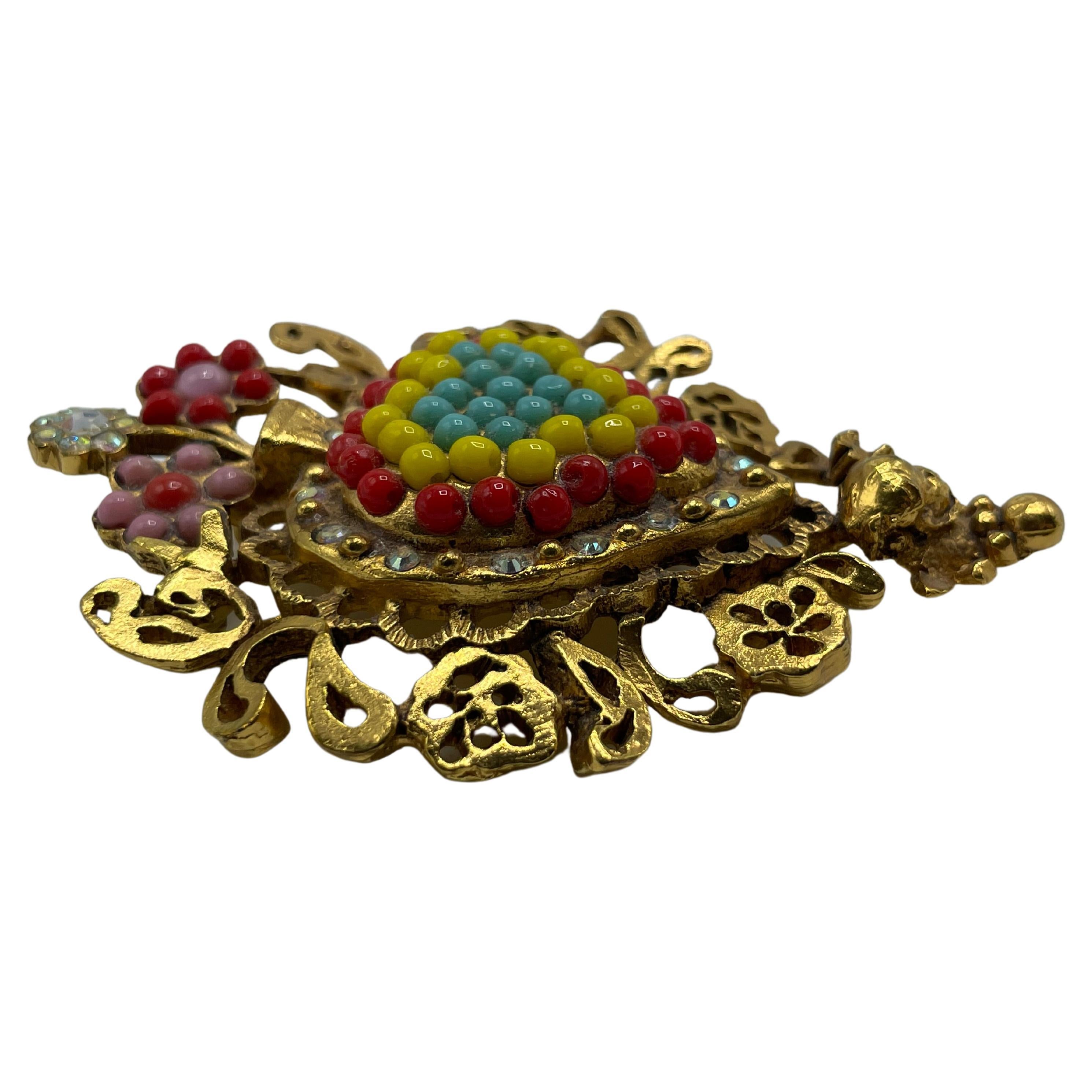 Christian Lacroix Vintage Gold Toned Brooch. A magnificent brooch in the shape of a red, blue, and yellow heart encircled by a row of rhinestones and gold bubbles. The center appears to be a vase holding three flowers.   Signature of Christian
