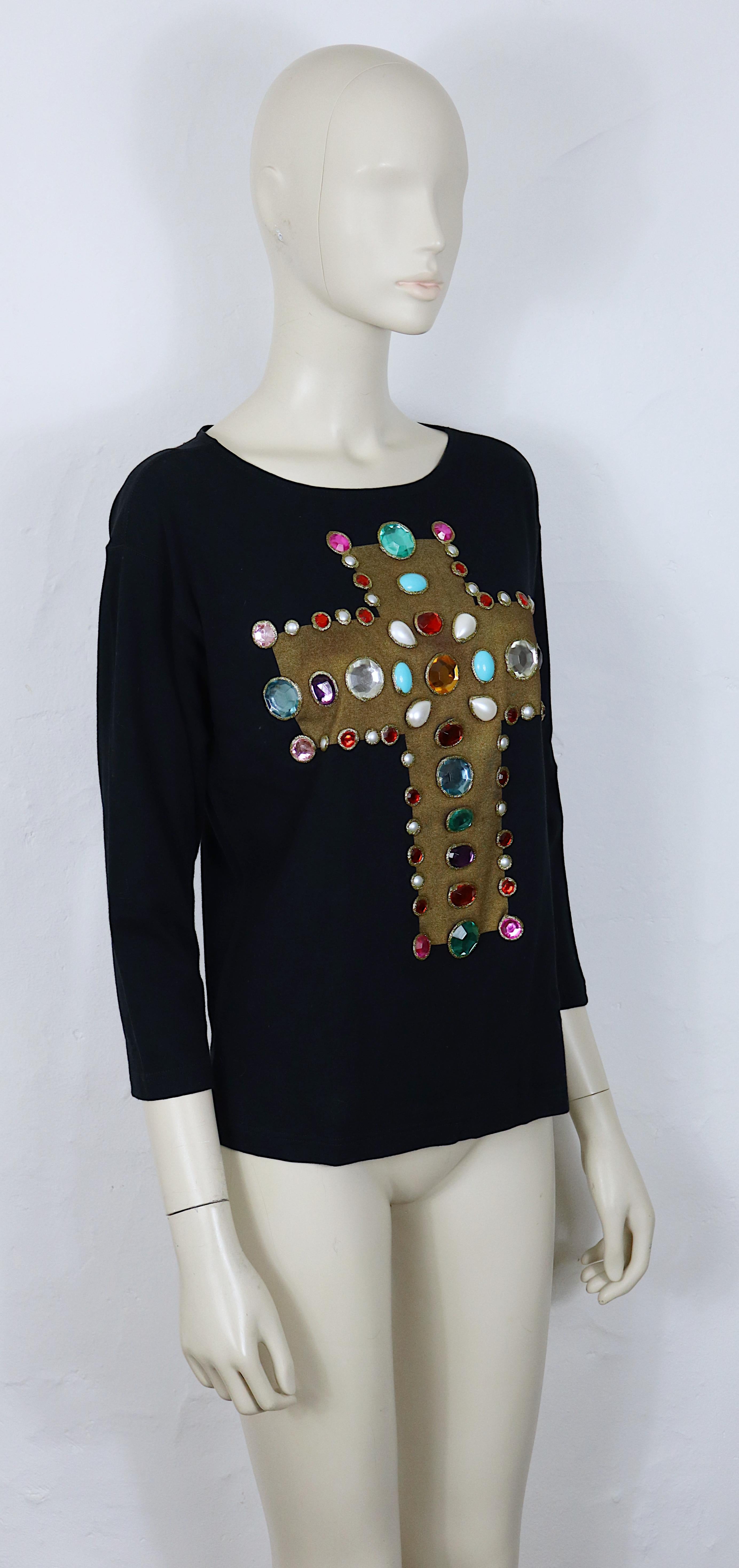 Camiseta de manga larga negra vintage icónica de CHRISTIAN LACROIX, con un atrevido y ornamentado motivo de cruz que recuerda la iconografía medieval, compuesto por adornos de resina en forma de gema en una rica paleta de colores.

Este top está