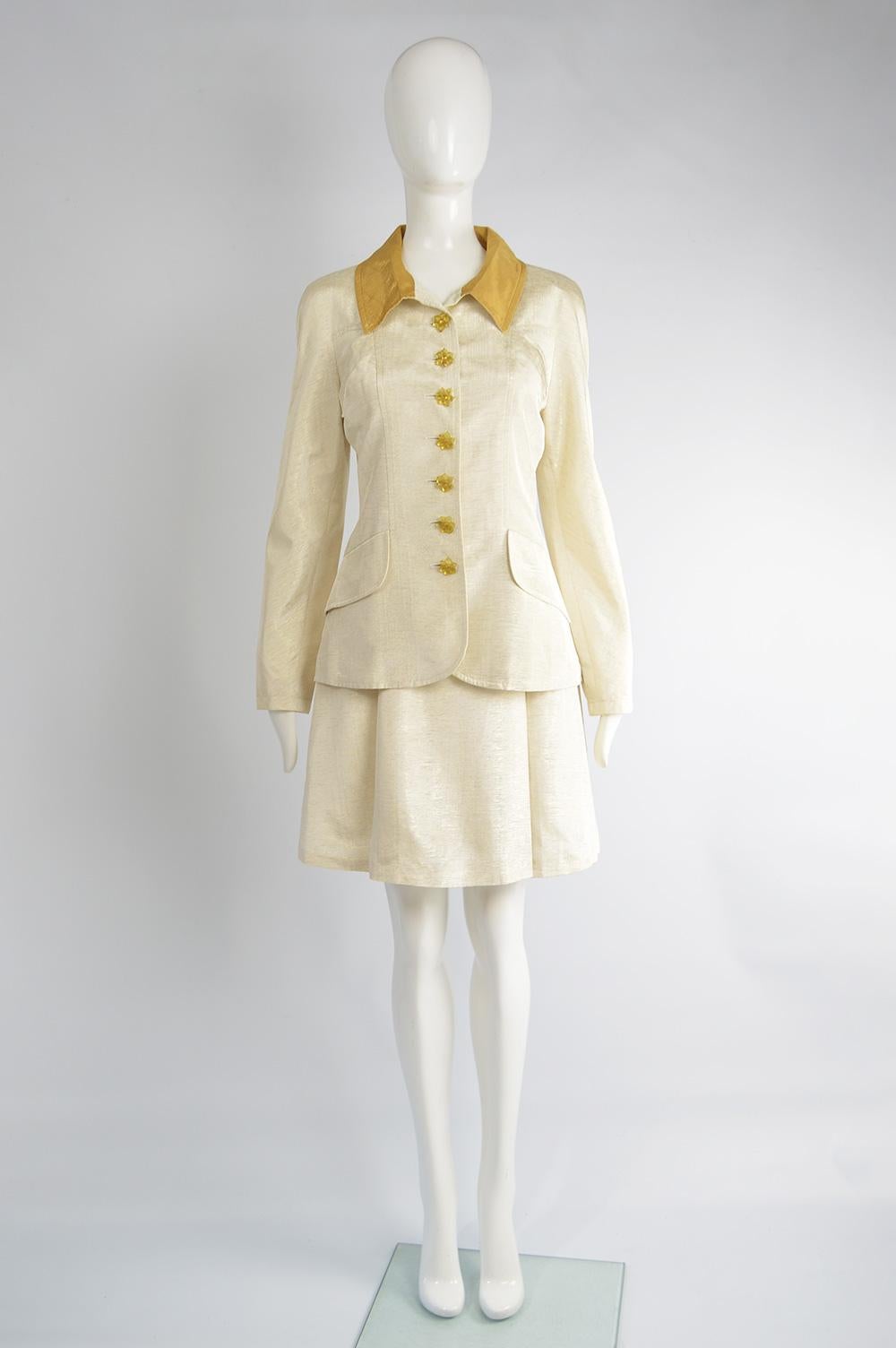 A fabulous vintage women's Christian Lacroix 2 piece skirt ensemble from the 90s. In an ivory coloured faille with a gold lamé collar and lucite buttons on the longline jacket and a matching high waisted skirt. Perfect for a party or as an unusual