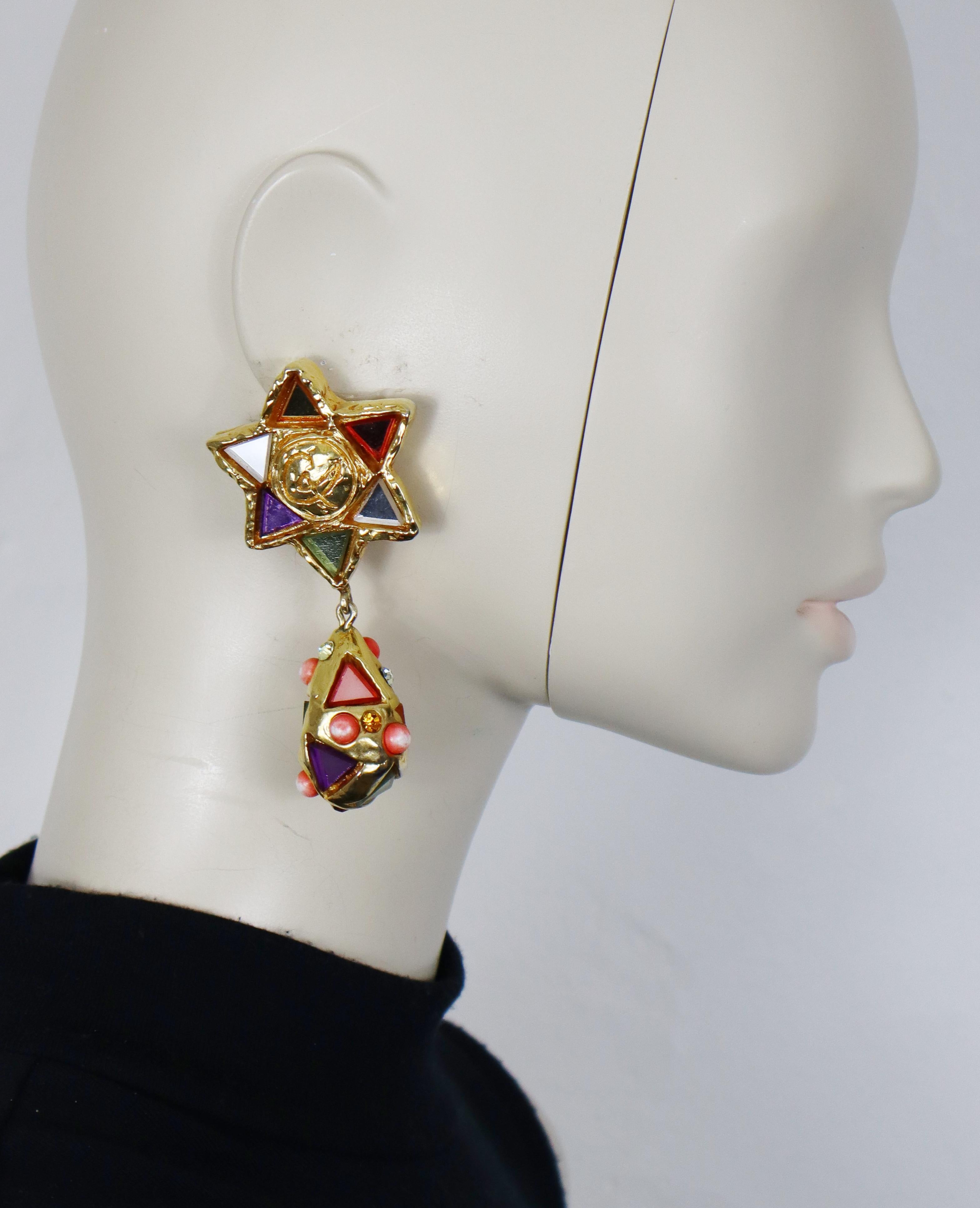 Pendientes colgantes vintage CHRISTIAN LACROIX de resina maciza en tono dorado (con clip), con una estrella estilizada en la parte superior y una gota adornada con espejos multicolores, cristales y cabujones acrílicos rosas.

Con la marca CHRISTIAN