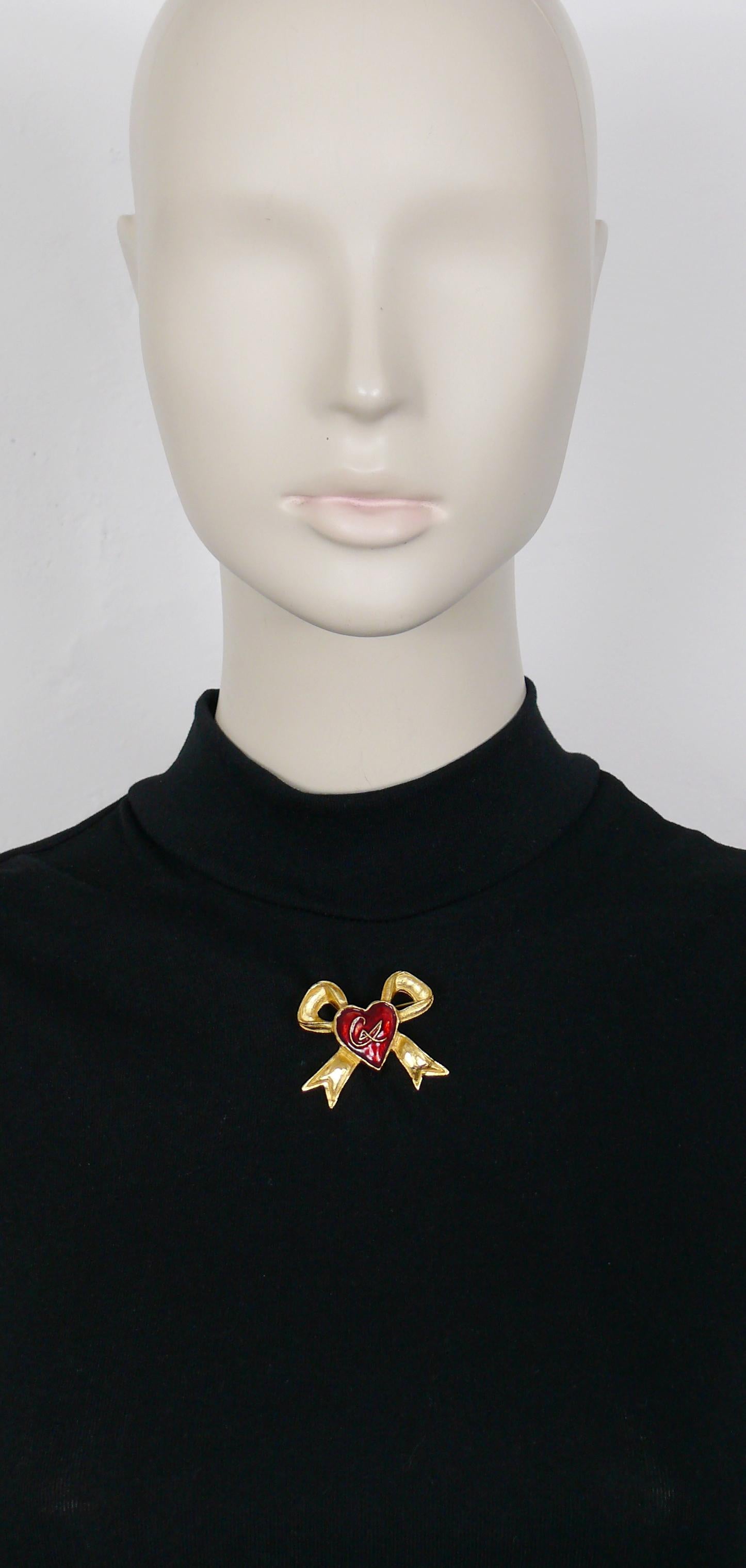 CHRISTIAN LACROIX Broche vintage con diseño de lazo de cinta en tono dorado con un corazón esmaltado en rojo en el centro con el monograma CL.

Con la marca CHRISTIAN LACROIX CL Fabricado en Francia.

Medidas orientativas: altura máxima aprox. 3,6