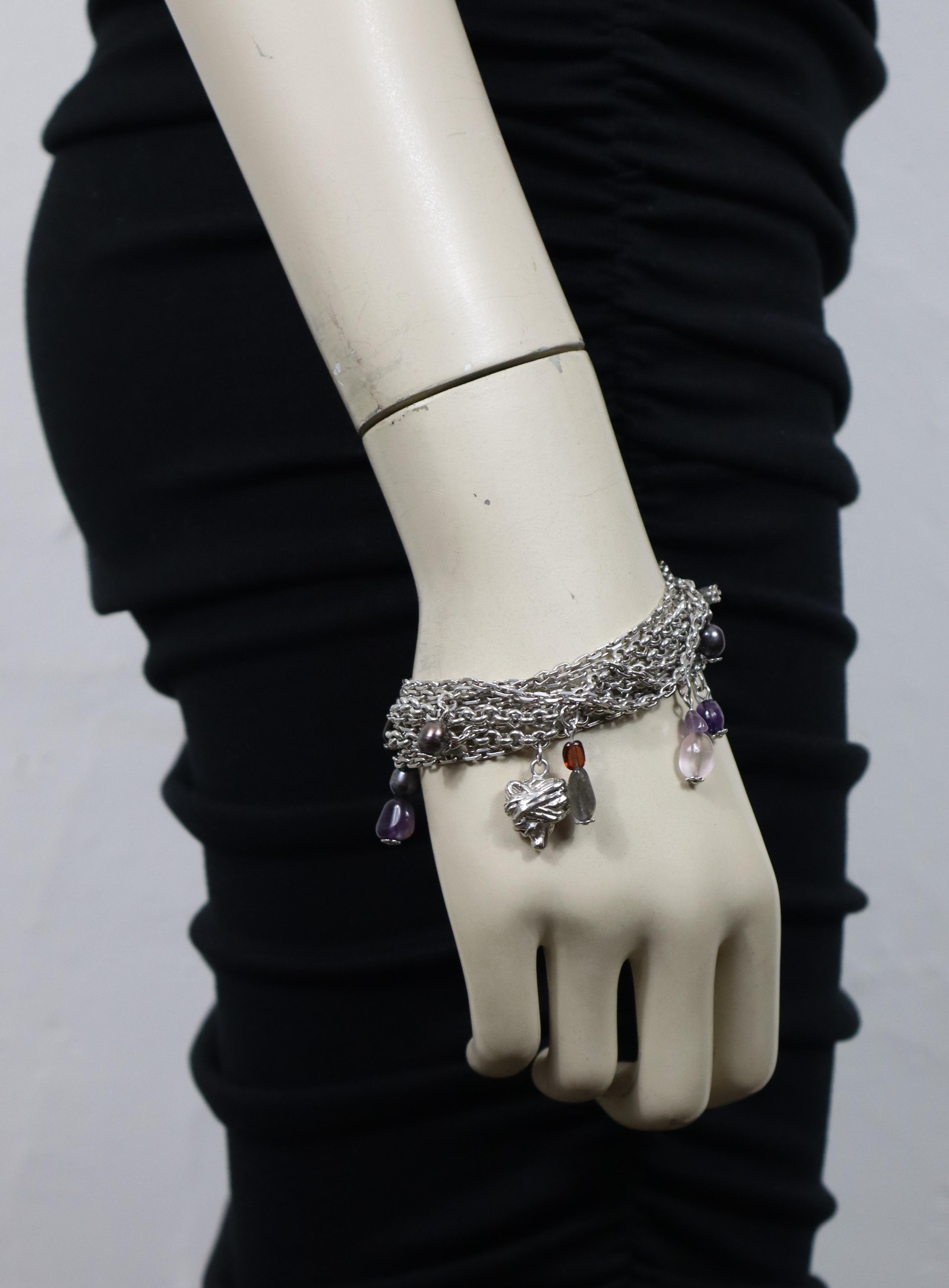 Bracciale vintage a catena in argento 925 di Christian Lacroix, ornato da pietre multicolori, perline iridescenti e un ciondolo a forma di cuore stilizzato.

La fibbia riporta la scritta CHRISTIAN Lacroix in rilievo.
Con impresso il marchio francese