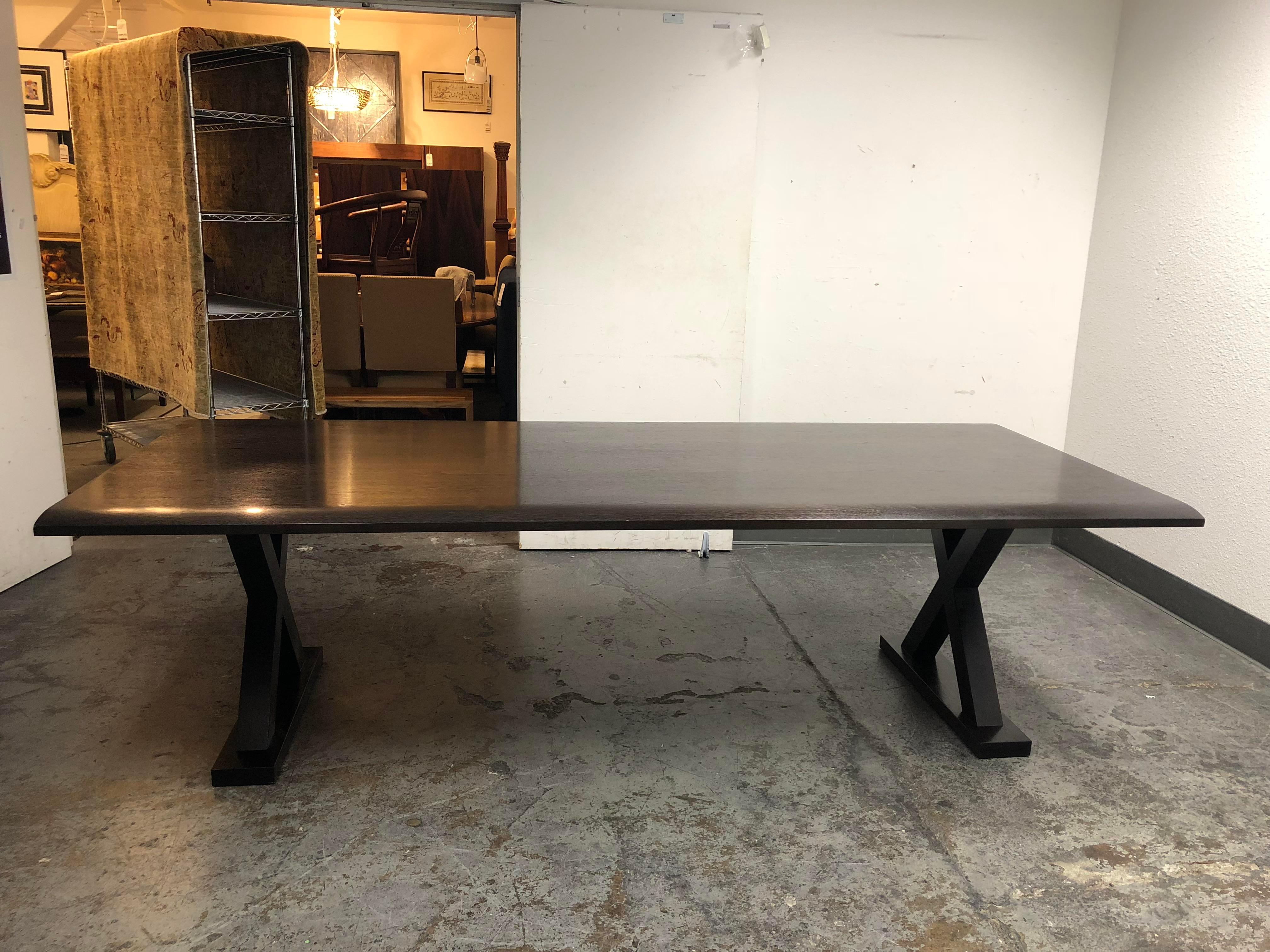 A custom-sized 'Courrier' table by Christian Liaigre for Holly Hunt. The bevelled edge tabletop is in an ebonized walnut with a dark espresso finish. Minor wear on edge. The table is supported by an X-frame trestle base.
 
 