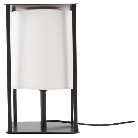 An original vintage “Lanterne” accent lamp designed by Christian Liaigre. The lamp was produced in the late 1990's/early 2000's, the design is currently discontinued. The lamp base and stem are patinated metal, the original lamp shade is off white