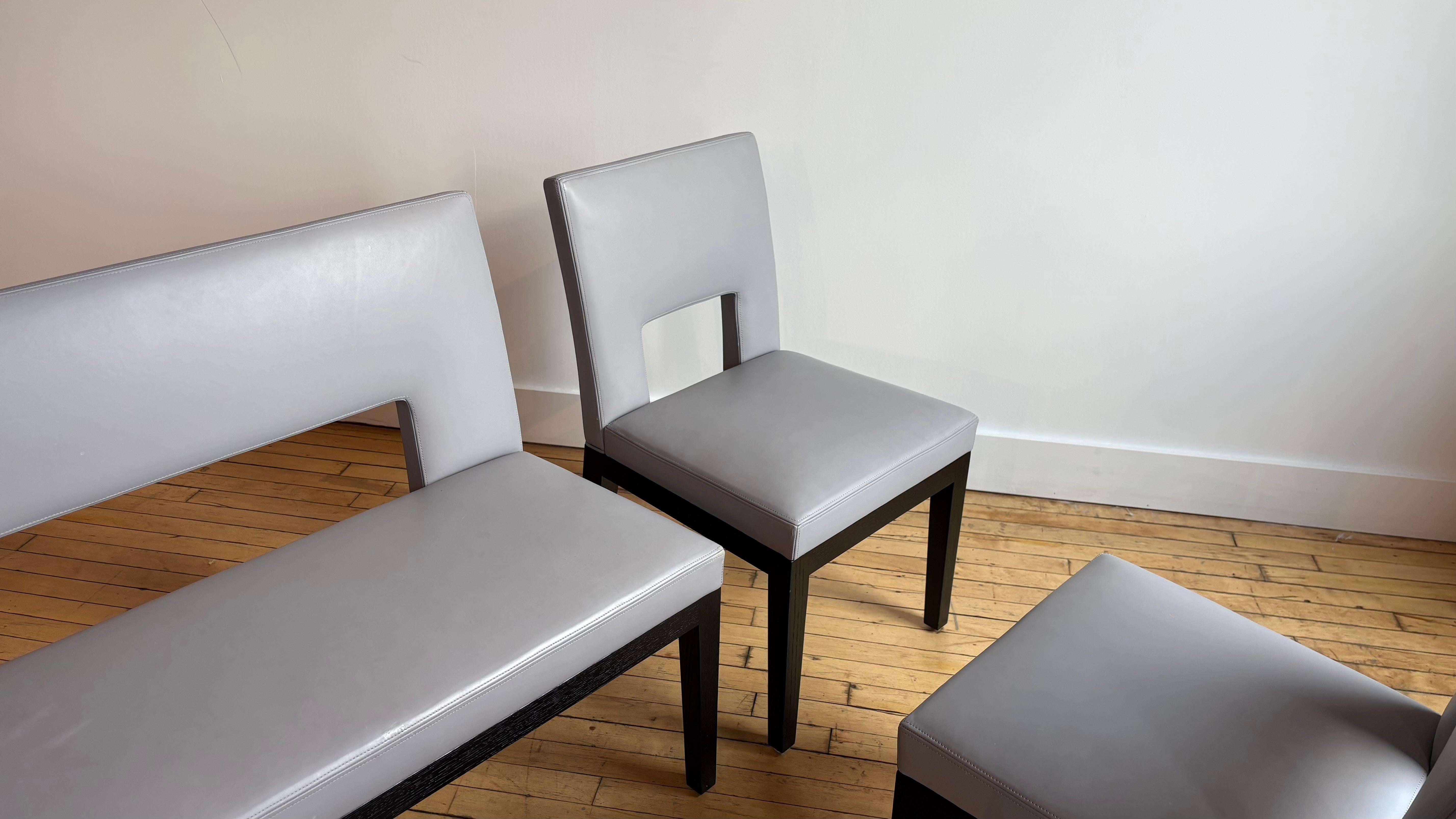 Fantastique ensemble de sièges de salle à manger composé de quatre chaises de salle à manger en cuir et d'une banquette en cuir assortie. 

Couleur bleu/gris avec des pieds en chêne noir.

Il s'agit du modèle Velin. Acheté en 2012 à Liaigre NYC.