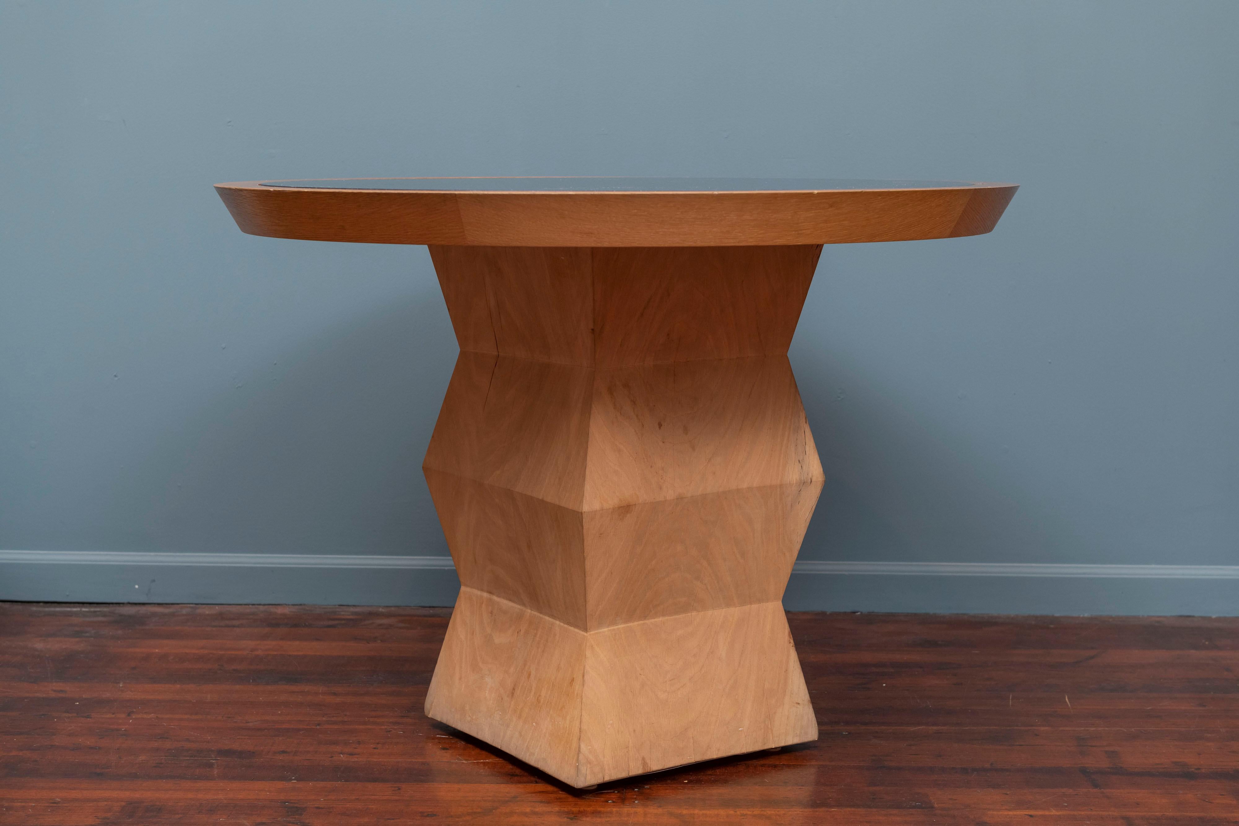 Christian Liaigre design Yquem pedestal table in solid oak with adapted black granite and oak top.
Small wood chip on pedestal base corner.