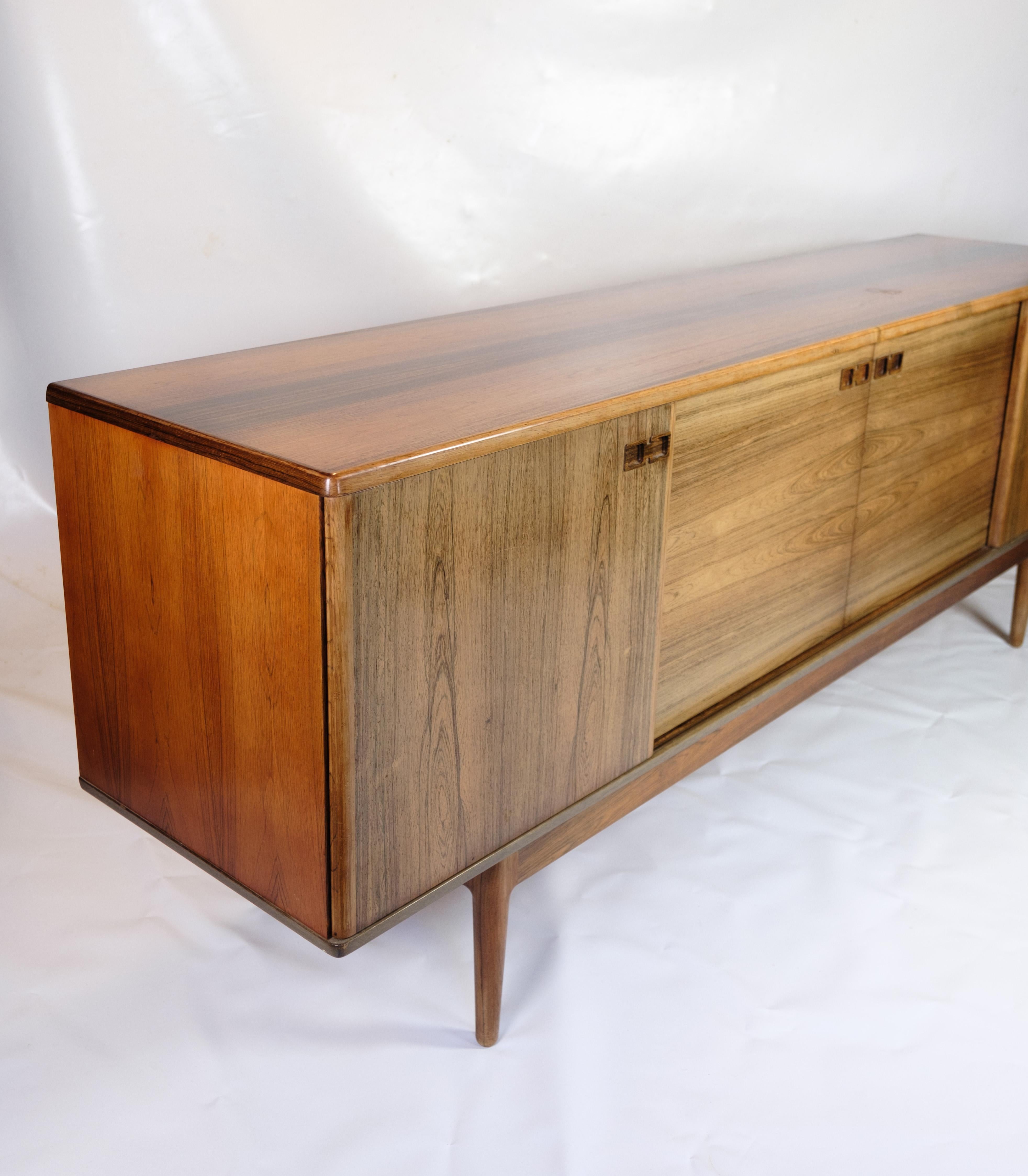Christian Linneberg made a low sideboard that is veneered with rosewood. It has four sliding doors on the front, behind which there are shelves and a pull-out tray. The sideboard stands on tapered legs and measures H. 83 cm, L. 225 cm, D. 50 cm. It