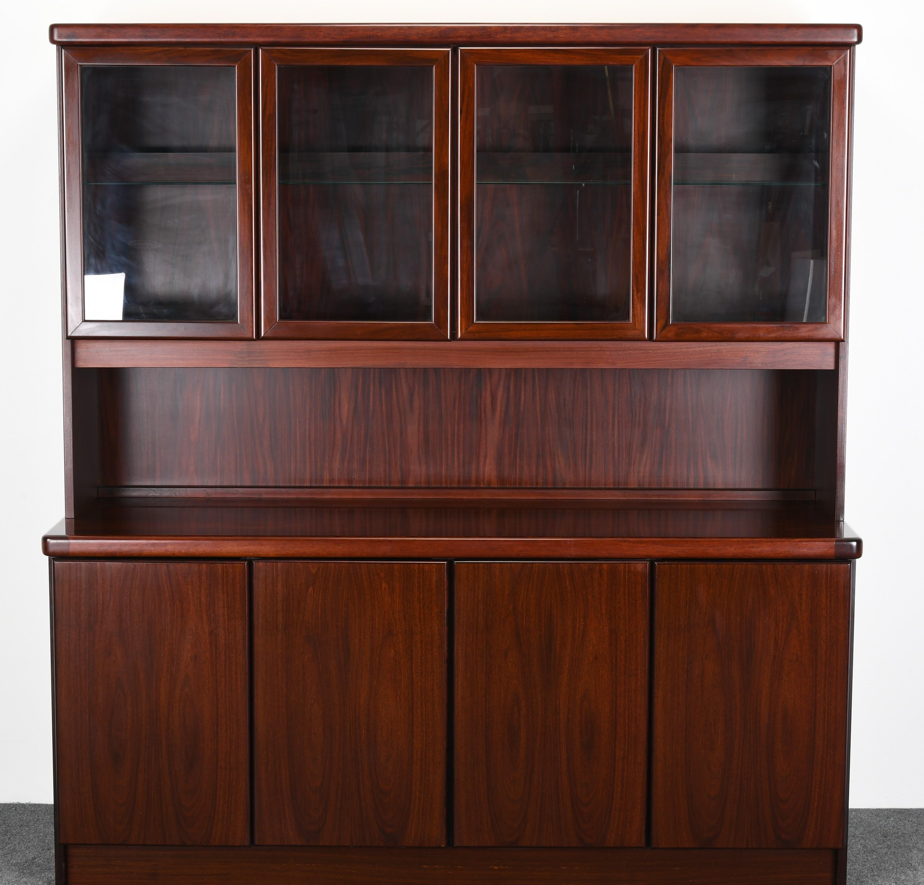 A gorgeous rosewood Danish buffet labeled Chr. Linneberg with glass front cabinets with interior and down lighting. The base has 4 doors, 4 shelves and 2 drawers for ample storage. The top has four doors and one interior glass shelf. The breakfront